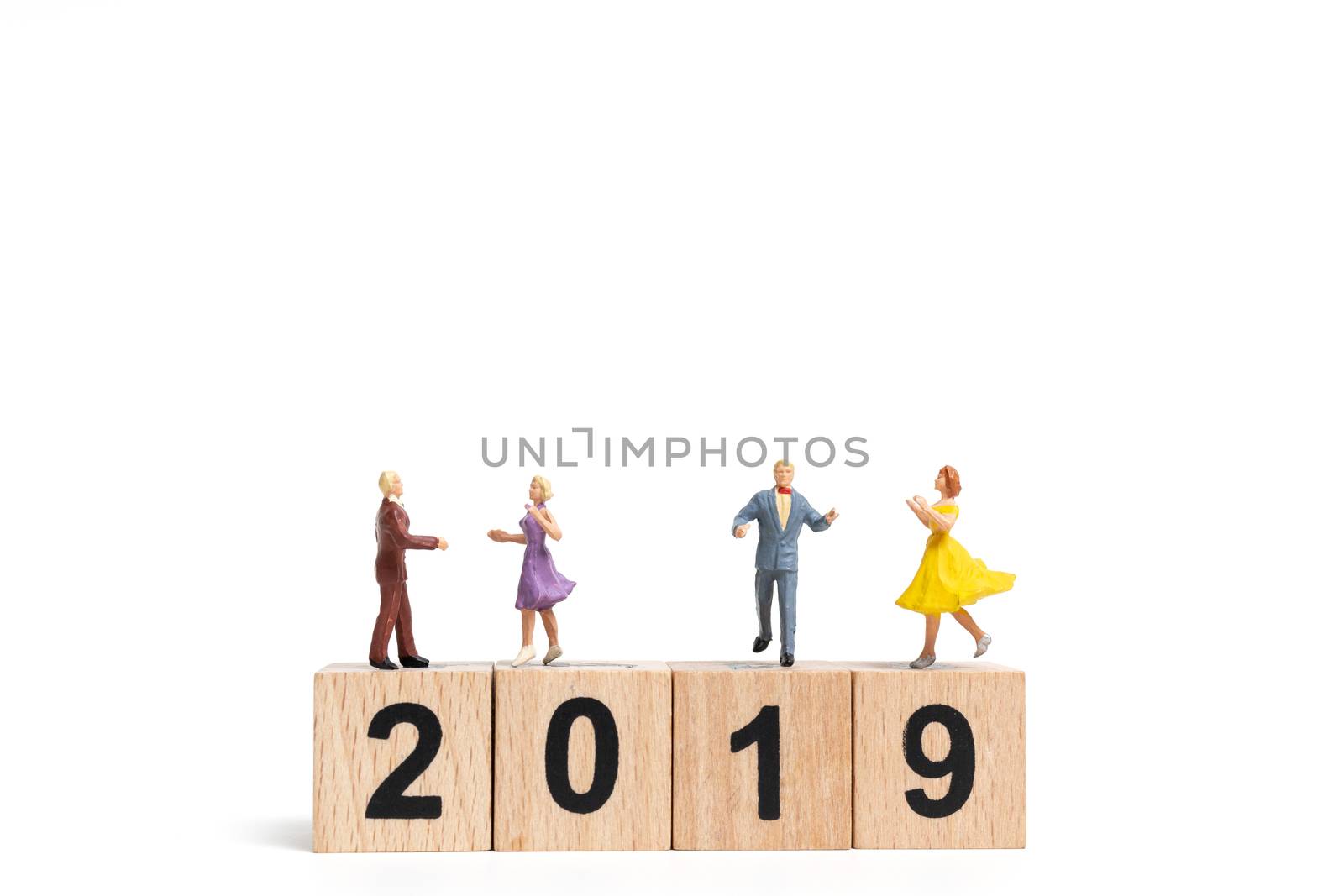 Miniature people dancing on wooden block number 2019. on white background