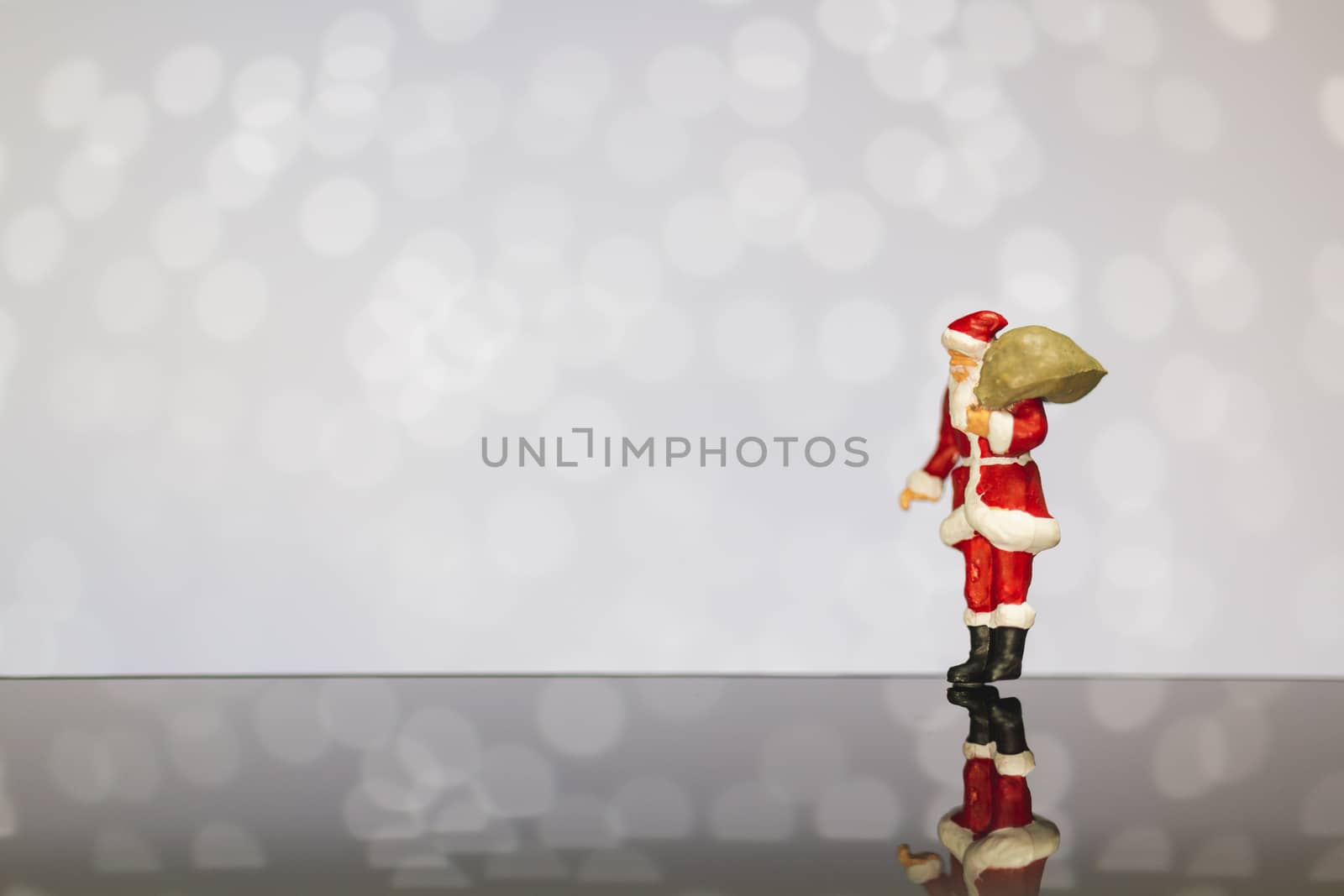 Miniature people : Santa Claus carrying bag  on bokeh  background , Merry Christmas and Happy New Year concept.