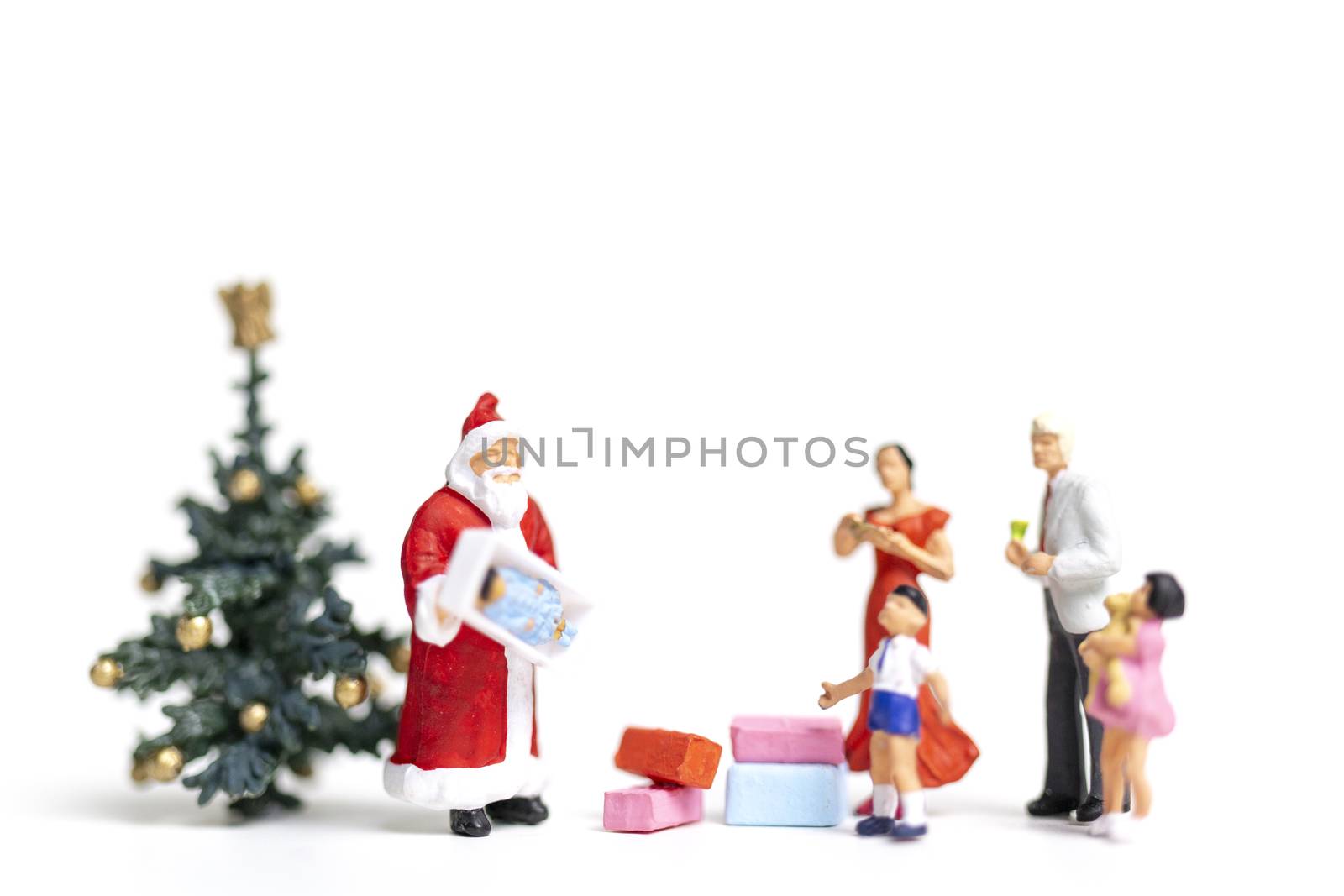 Miniature people : Santa Claus holding gift for happy family , Christmas and Happy New Year concept.