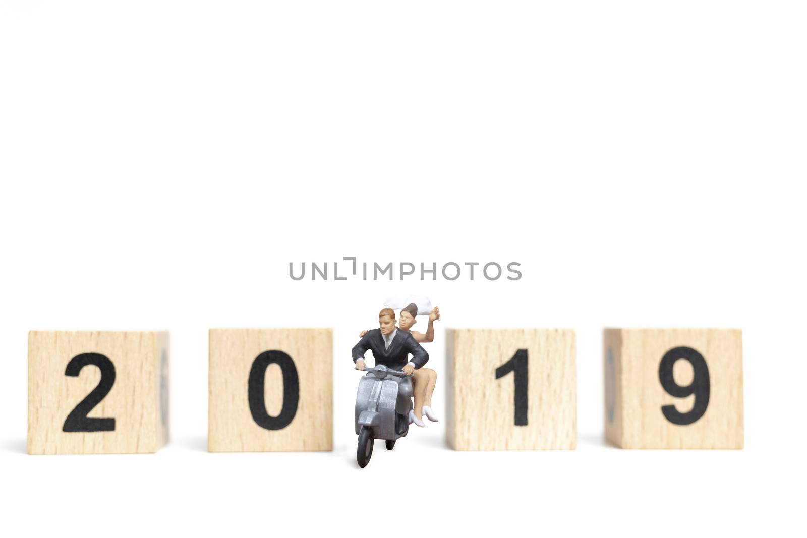 Miniature people : Couple riding the motorcycle on white background  with wooden block 2019