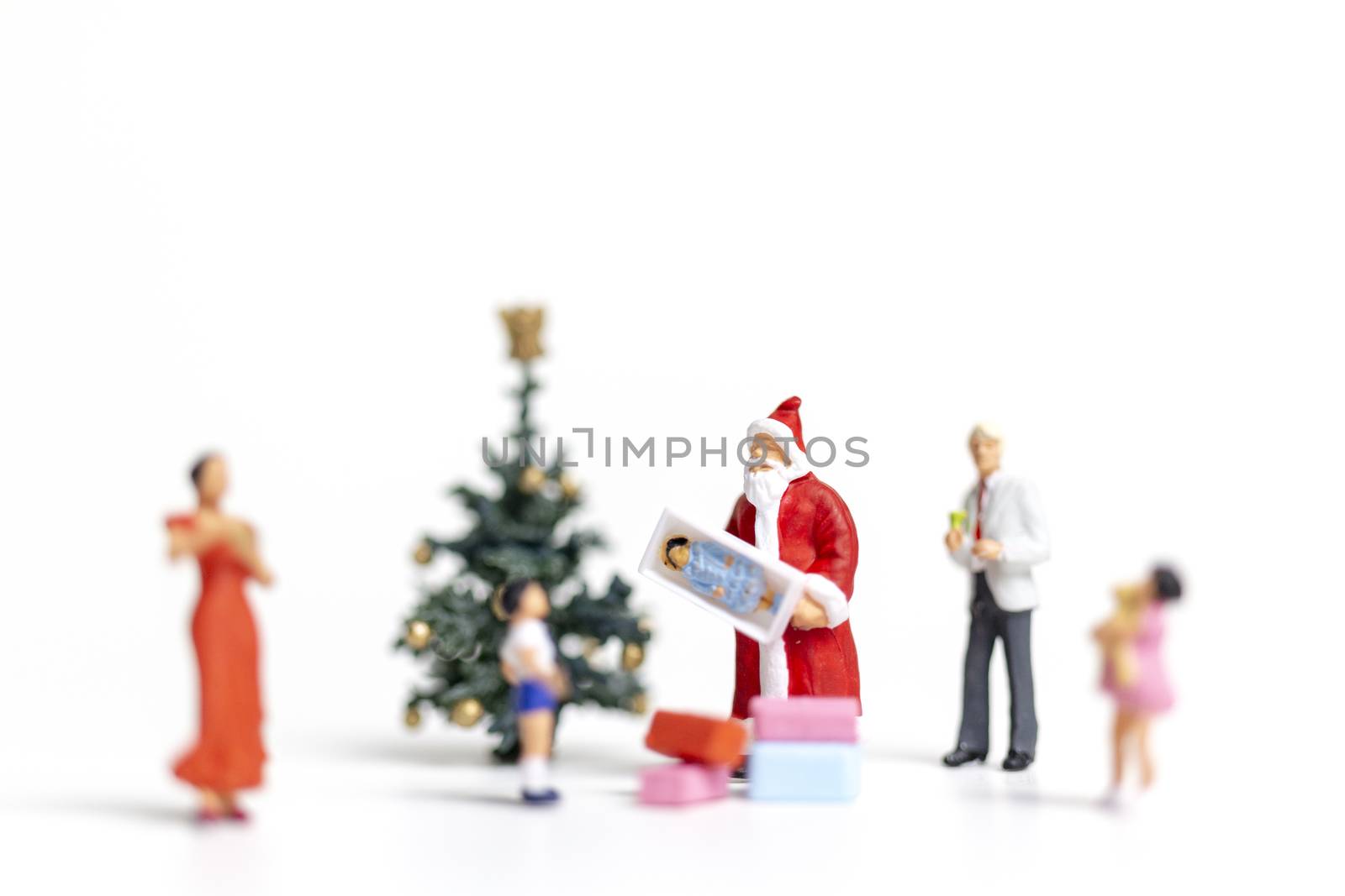 Miniature people : Santa Claus holding gift for happy family , Christmas and Happy New Year concept.