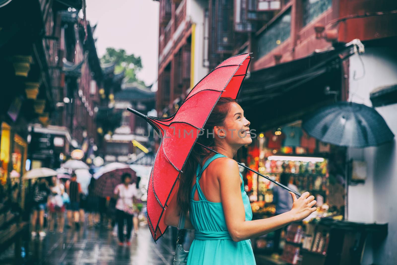 People lifestyle umbrella travel Asian woman shopping in chinatown market street. Rainy day girl tourist under red oriental umbrella in back alleys in Shanghai, China by Maridav