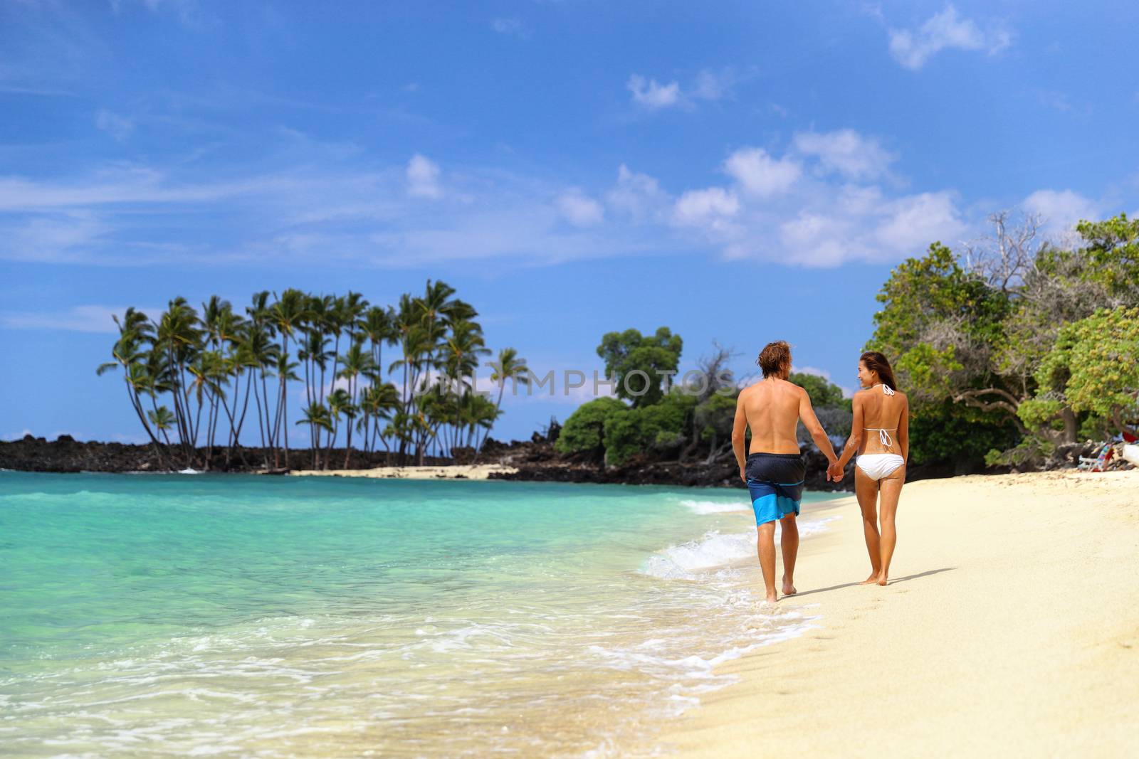 Honeymoon travel beach vacation couple walking holding hands on Hawaii summer holidays.