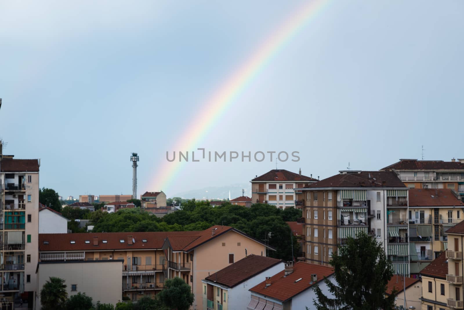 Turin, Piedmont, Italy. June 2020. After a summer storm in the northern suburbs, a rainbow emerges from the roof of a small house on the horizon and embraces the city.