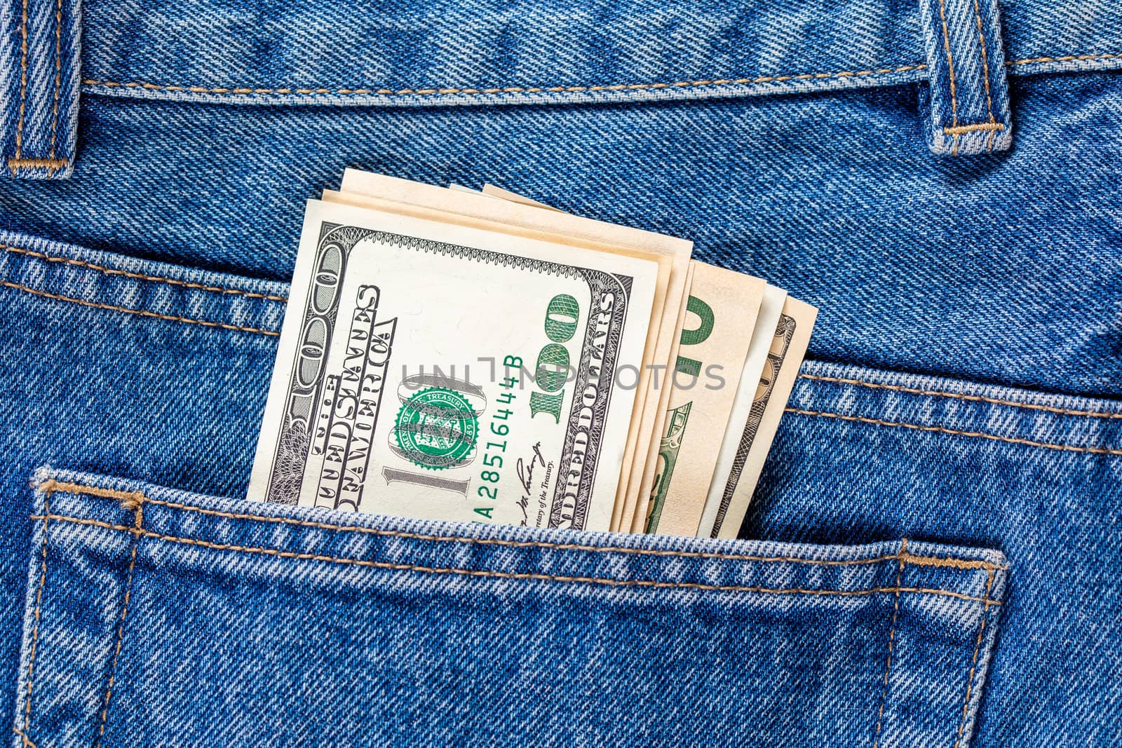 US dollar banknotes in the left rear pocket of blue jeans. Concept of saving money or pocket expenses by z1b