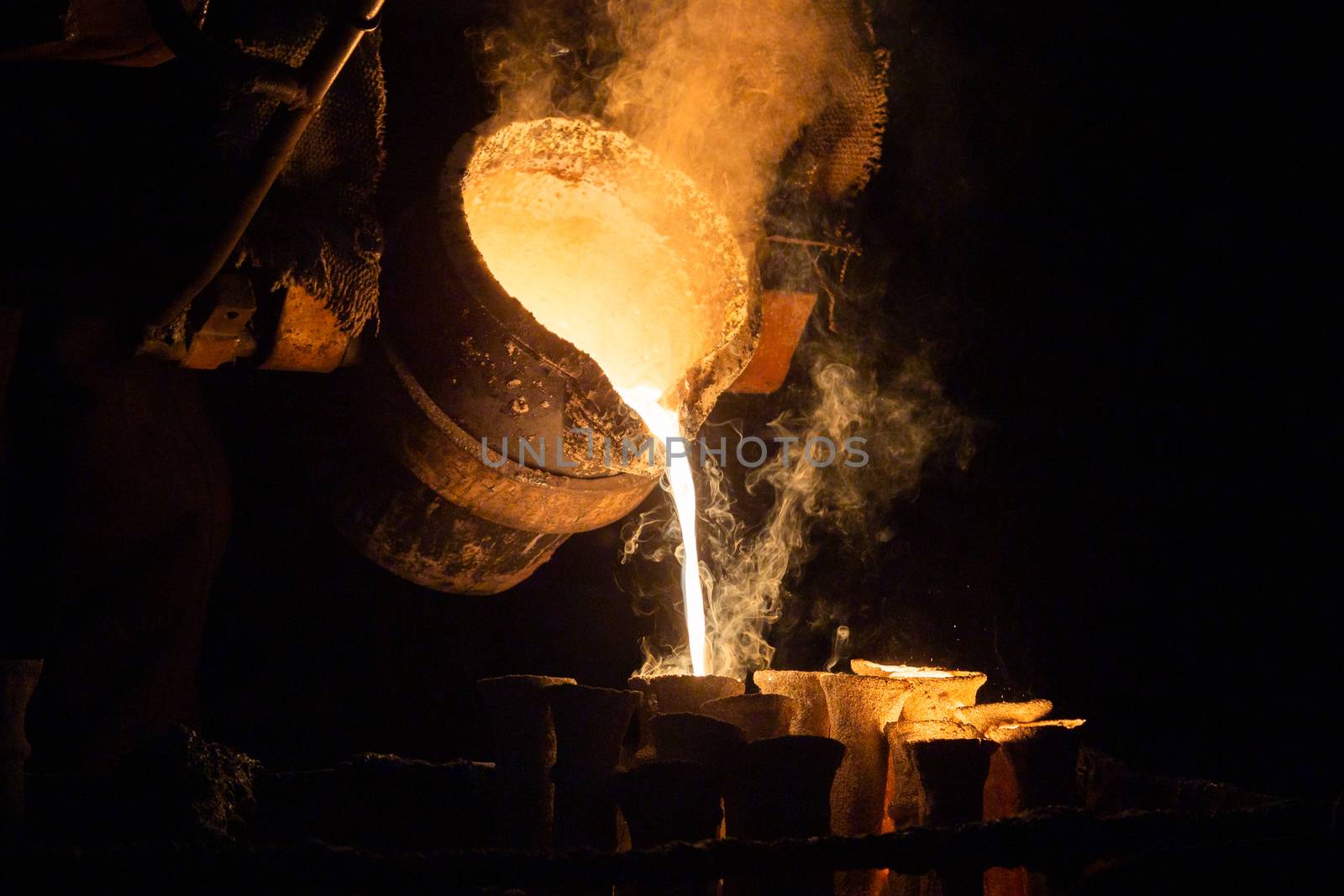 Industrial lost wax casting. The process of pouring for filling out ceramic shells with molten steel from ladle.