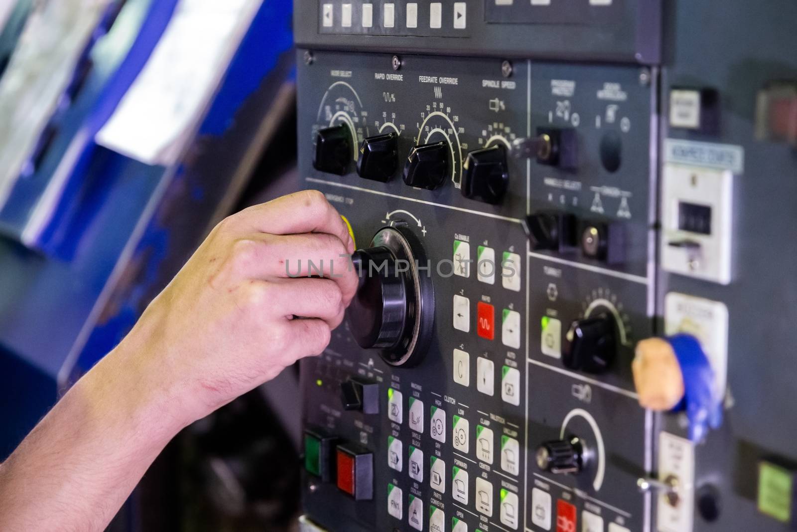 Human operator hand spinning jog handle on CNC machine control panel. Close-up with selective focus and blur. Real picture from industrial manufacture