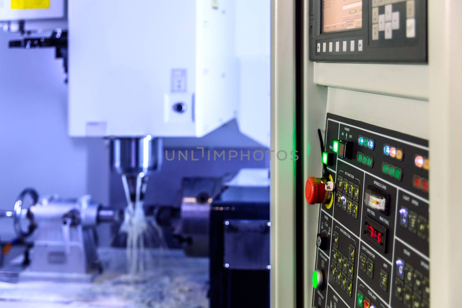 A modern 4-axis cnc vertical milling machine working with water cooling, selective focus on foreground, blur on background,