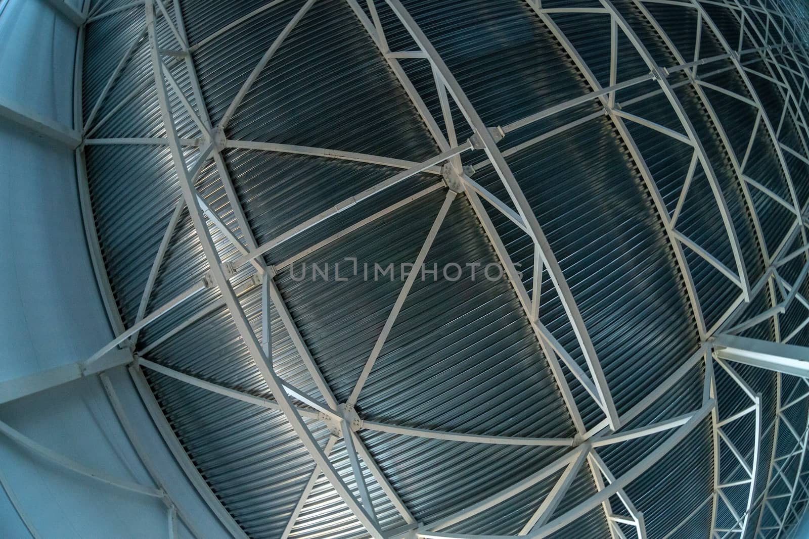 A heavy distortrd fish-eye lens picture of industrial ceiling with supporting beam construction frame and profiled sheets. Zenith direction of view.