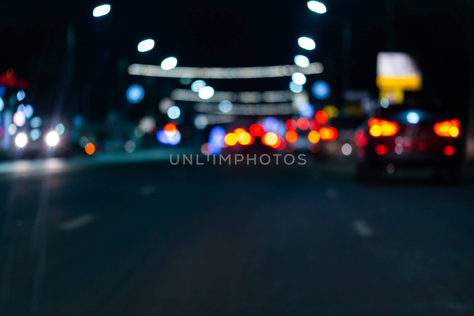 Defocused picture of night street car traffic - view from road. Colorful night life dark background.