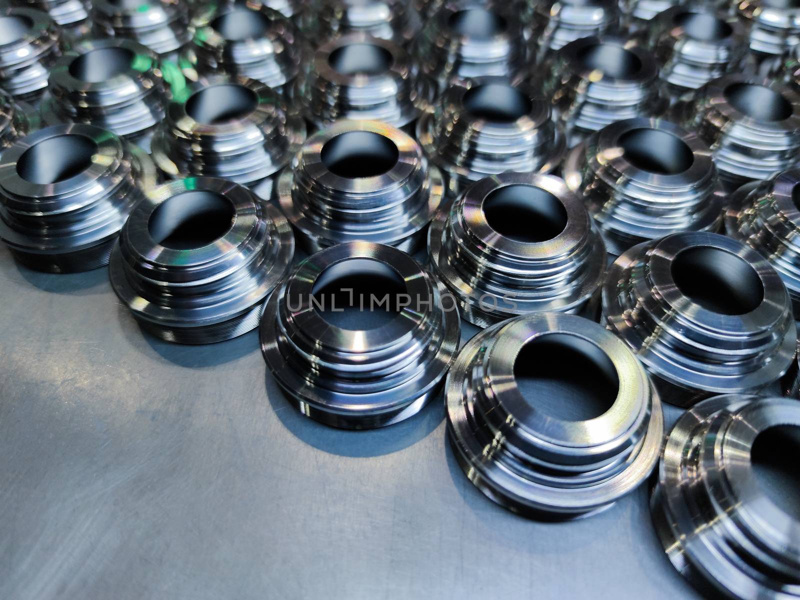 Shiny steel parts background. An edge of metal cnc turning production batch laid bin rows on flat brushed iron surface.