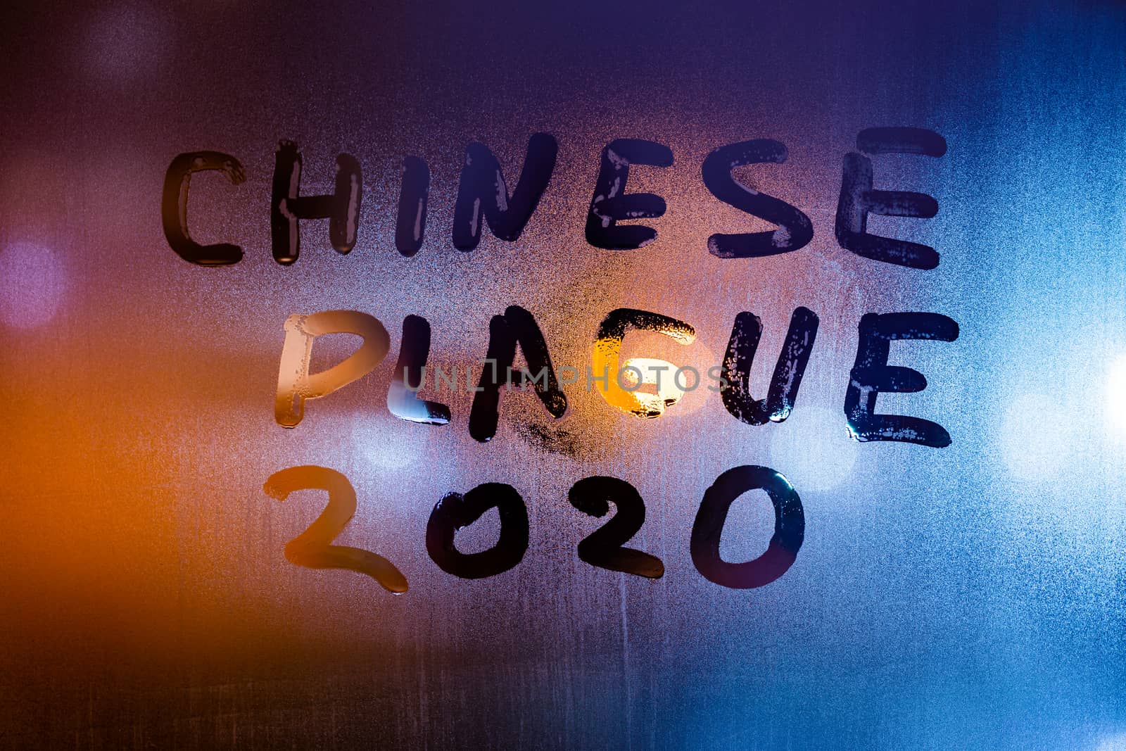 The words chinese plague 2020 handwritten on sweat window glass surface at night. Pandemic concept.