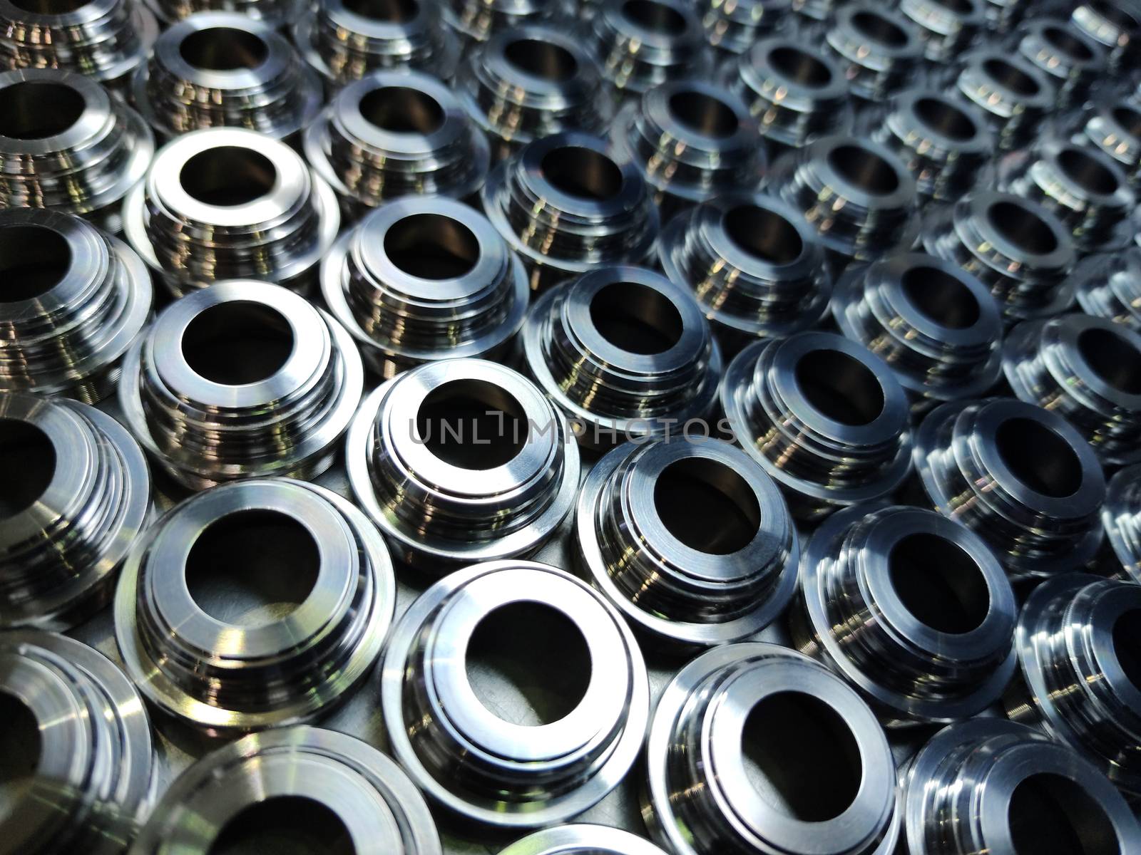 Shiny silver color stainless steel parts background. Regular industrial metal production pattern with selective focus and background blur.