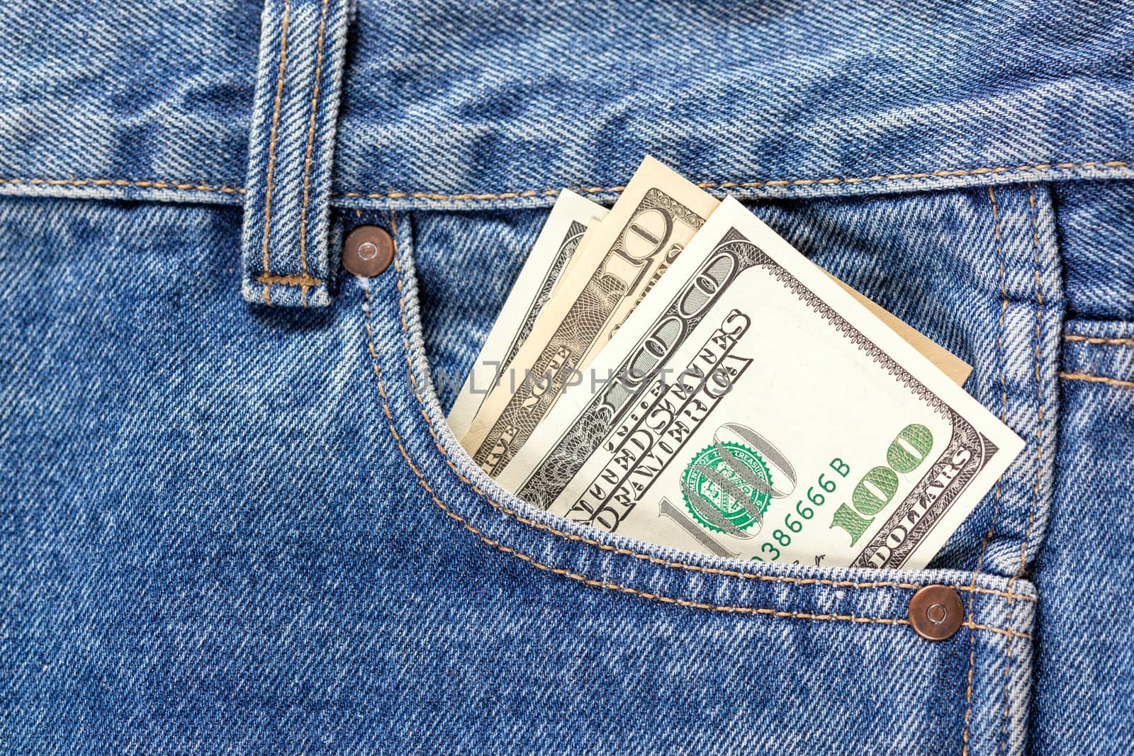 US dollar banknotes in the right front pocket of blue jeans. Concept of saving money or pocket expenses by z1b