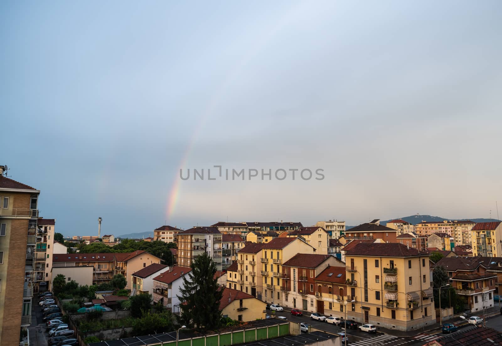 Turin, Piedmont, Italy. June 2020. After a summer storm in the northern suburbs, a rainbow emerges from the roof of a small house on the horizon and embraces the city.