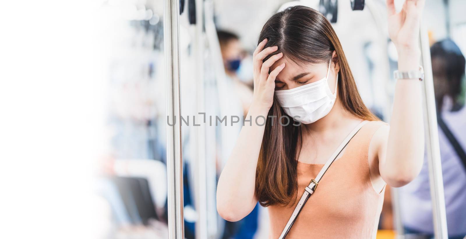 Young Asian woman passenger wearing surgical mask and Having a headache in subway train when traveling in big city at Covid19 outbreak, Infection and Pandemic,new normal and illness prevention concept