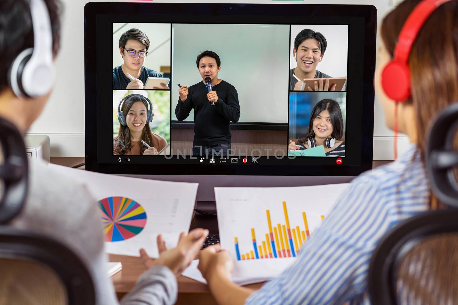 Rear view of Asian partner working and online meeting via video by Tzido