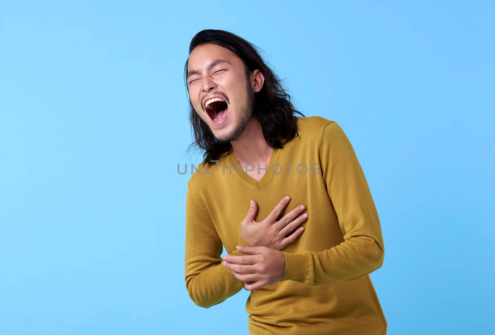 Young Asian man happy with laugh face on blue background.