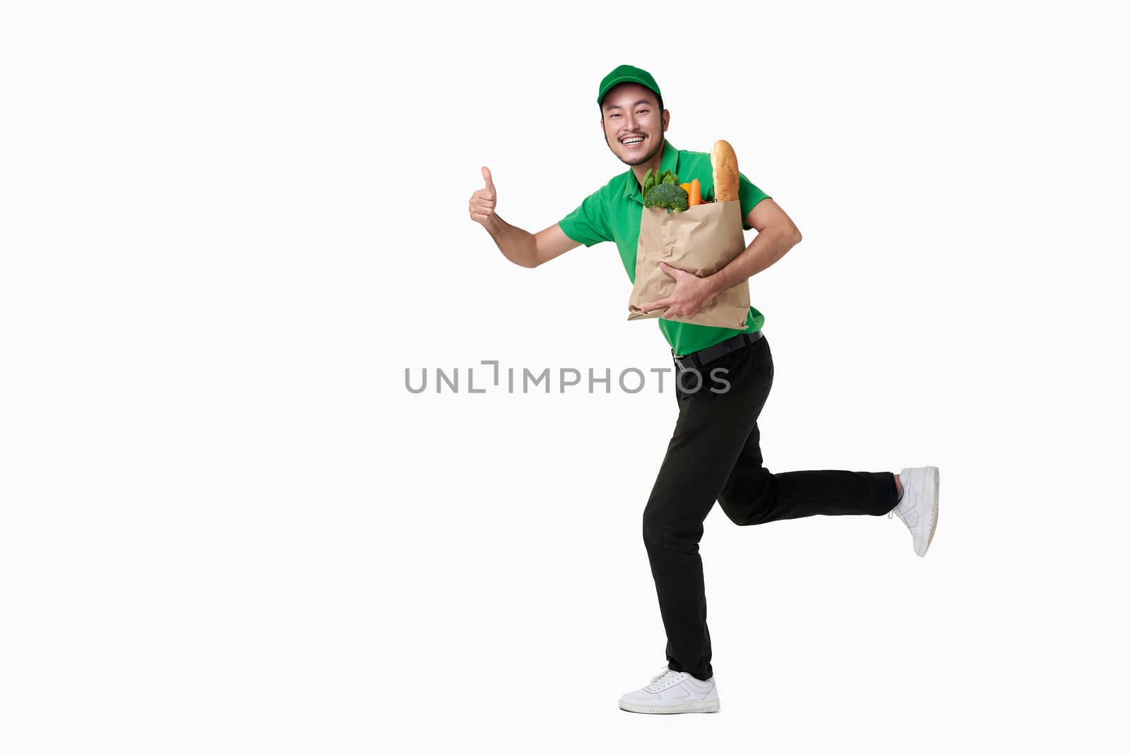 Asian delivery man wearing in green uniform holding fresh food paper bag isolated over white background. by barameeyay