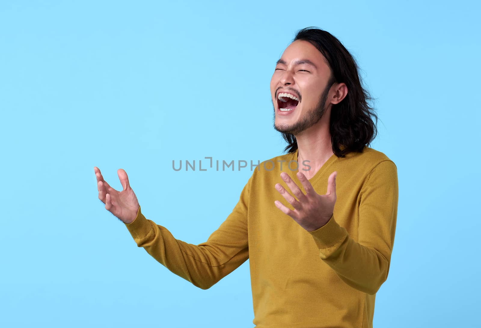 Young Asian man happy with laugh face on blue background. by barameeyay