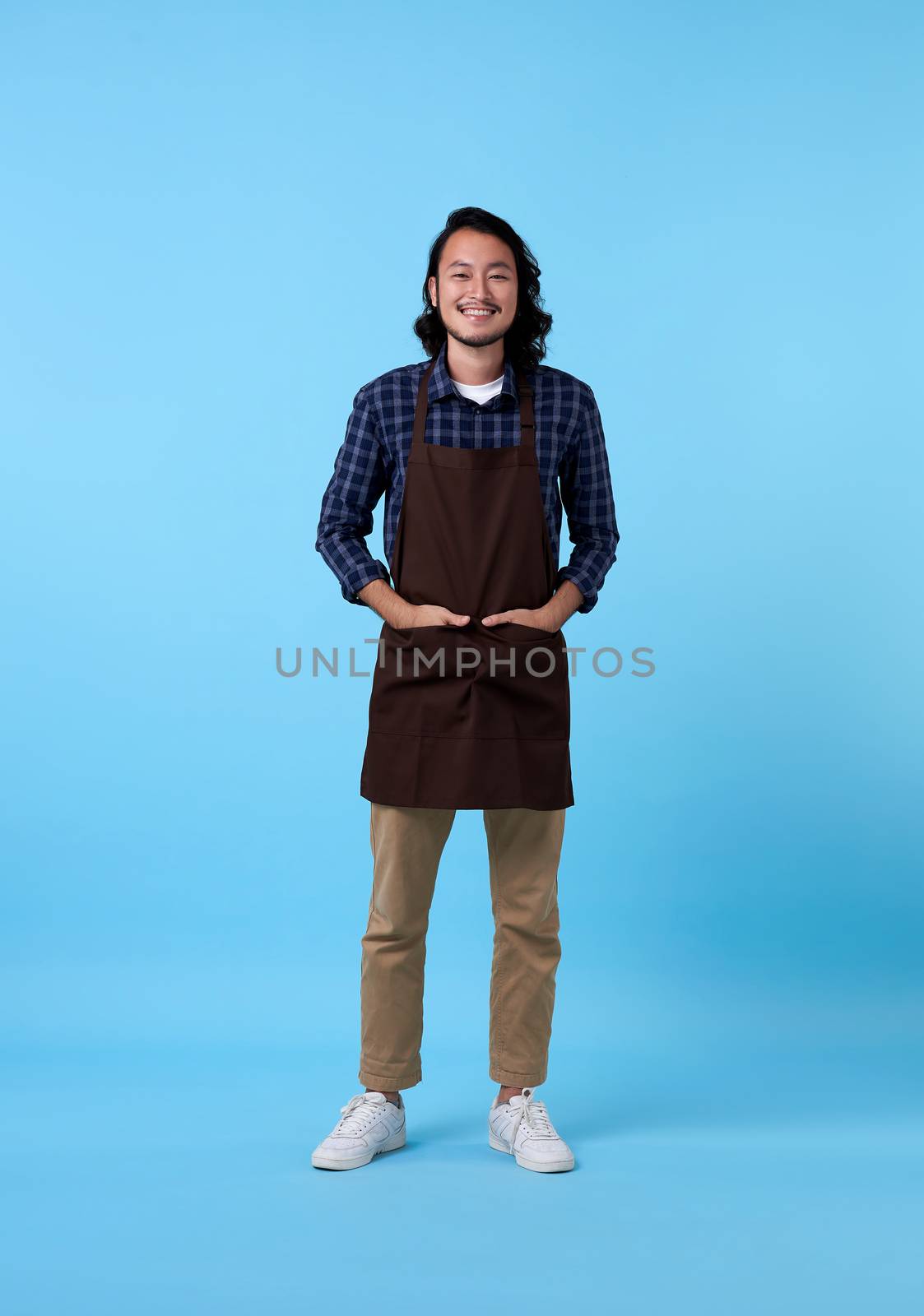 Portrait of service minded handsome asian man employee studio shot on blue background by barameeyay