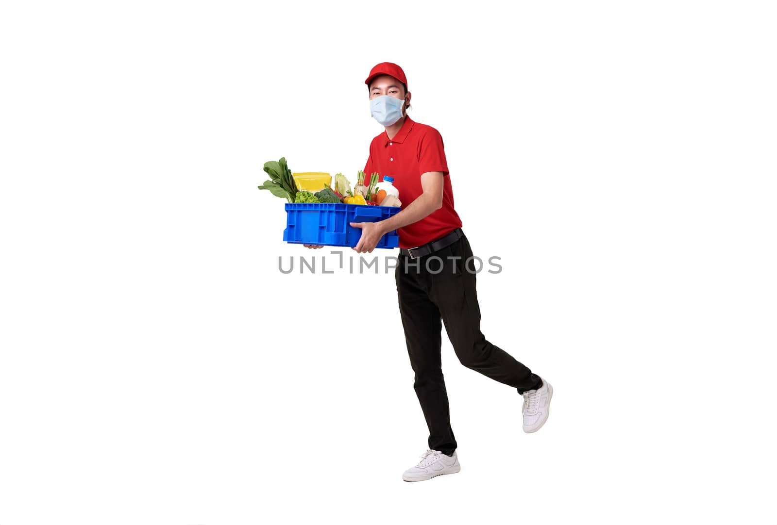 Asian delivery man wearing face mask in red uniform holding fresh food basket isolated over white background. express delivery service during covid19. by barameeyay