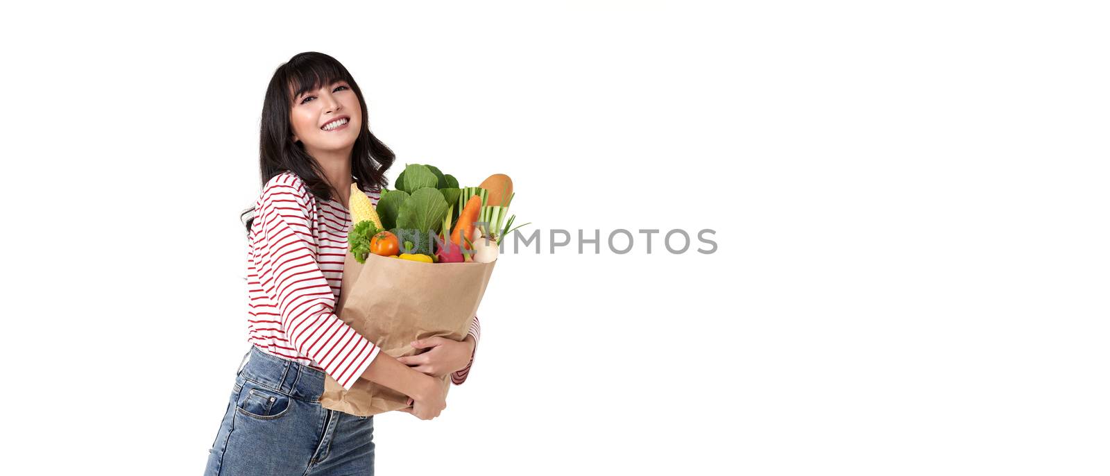 Happy smiling Asian woman holding paper shopping bag full of vegetables isolated on banner background with copy space.