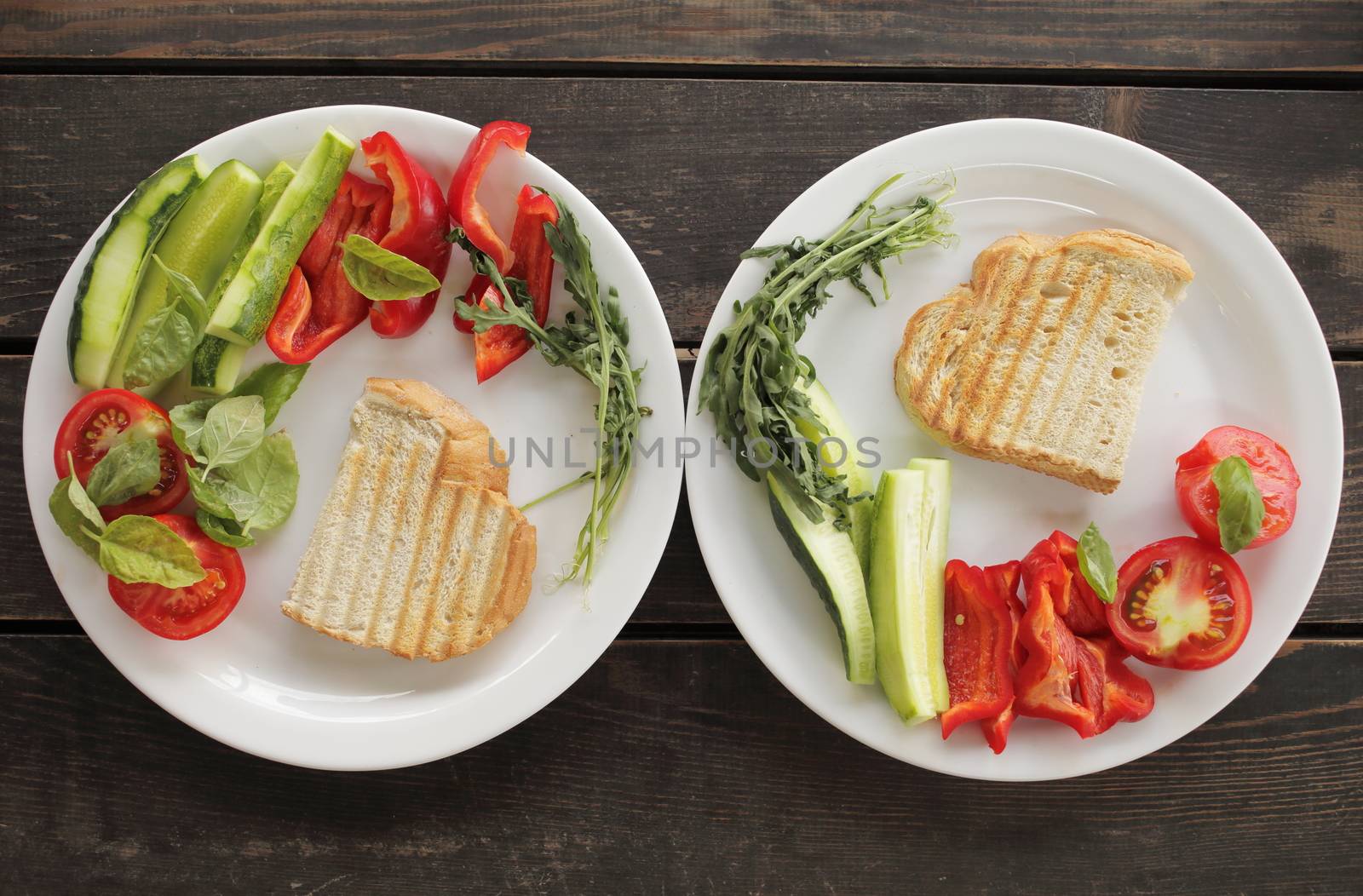 Healthy organic vegetable breakfast, tomato, toast, salad, basil, cucumber, arugula. Vegetarian healthy food in a white plate on a dark wooden table. High quality photo