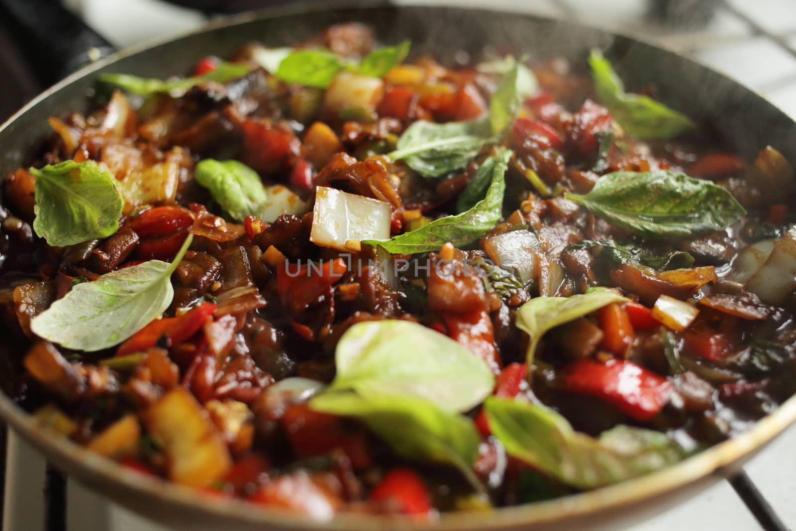 Healthy food, vegetables are fried in a pan. Tomato eggplant onion pepper zucchini basil. Steam
