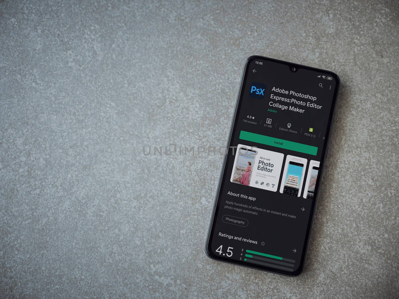 Lod, Israel - July 8, 2020: Adobe Photoshop Express Photo Editor app play store page on the display of a black mobile smartphone on ceramic stone background. Top view flat lay with copy space.