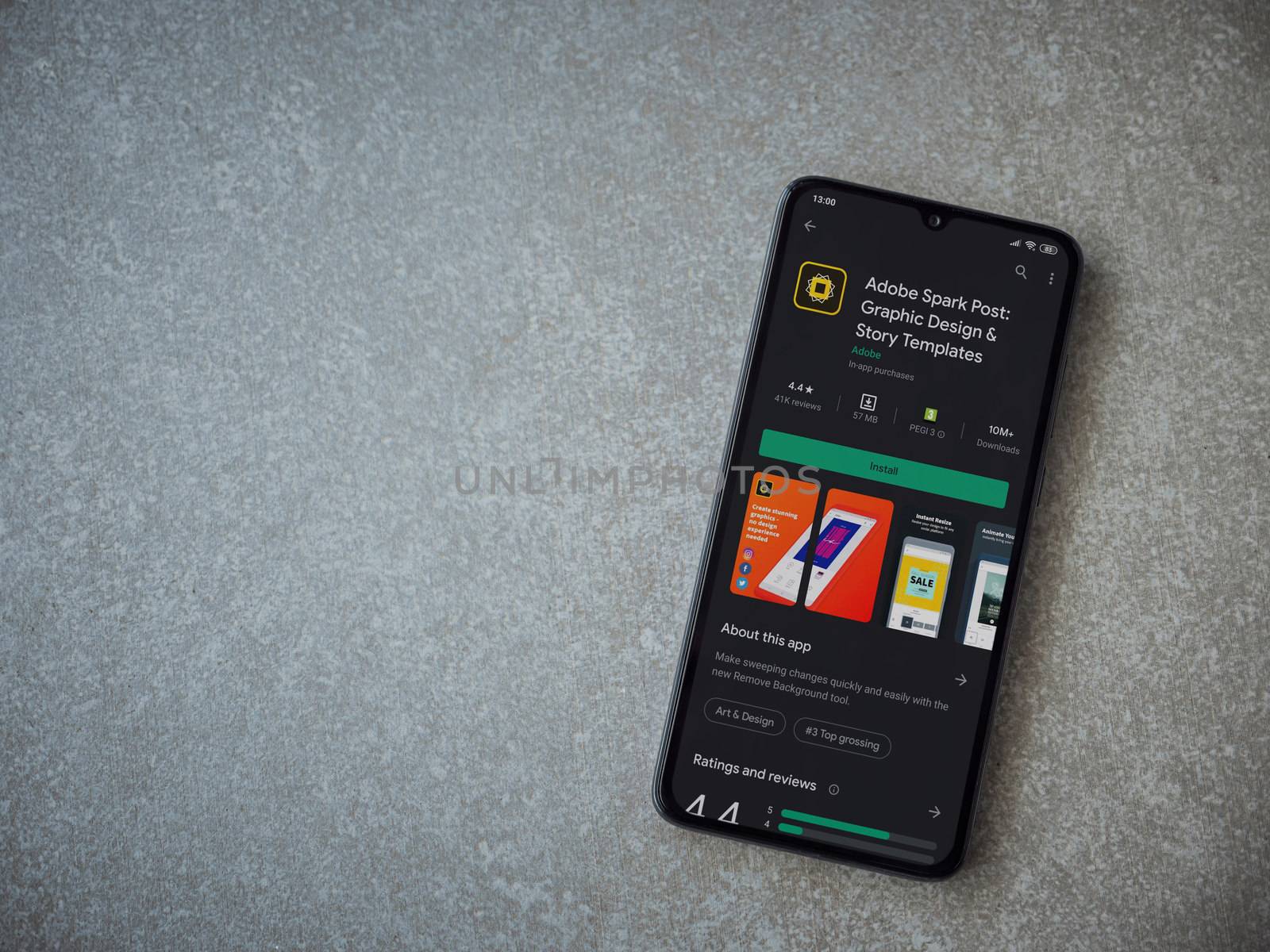 Lod, Israel - July 8, 2020: Adobe Spark Post - Graphic Design and Story Templates app play store page on the display of a black mobile smartphone on ceramic stone background.Top view flat lay with copy space