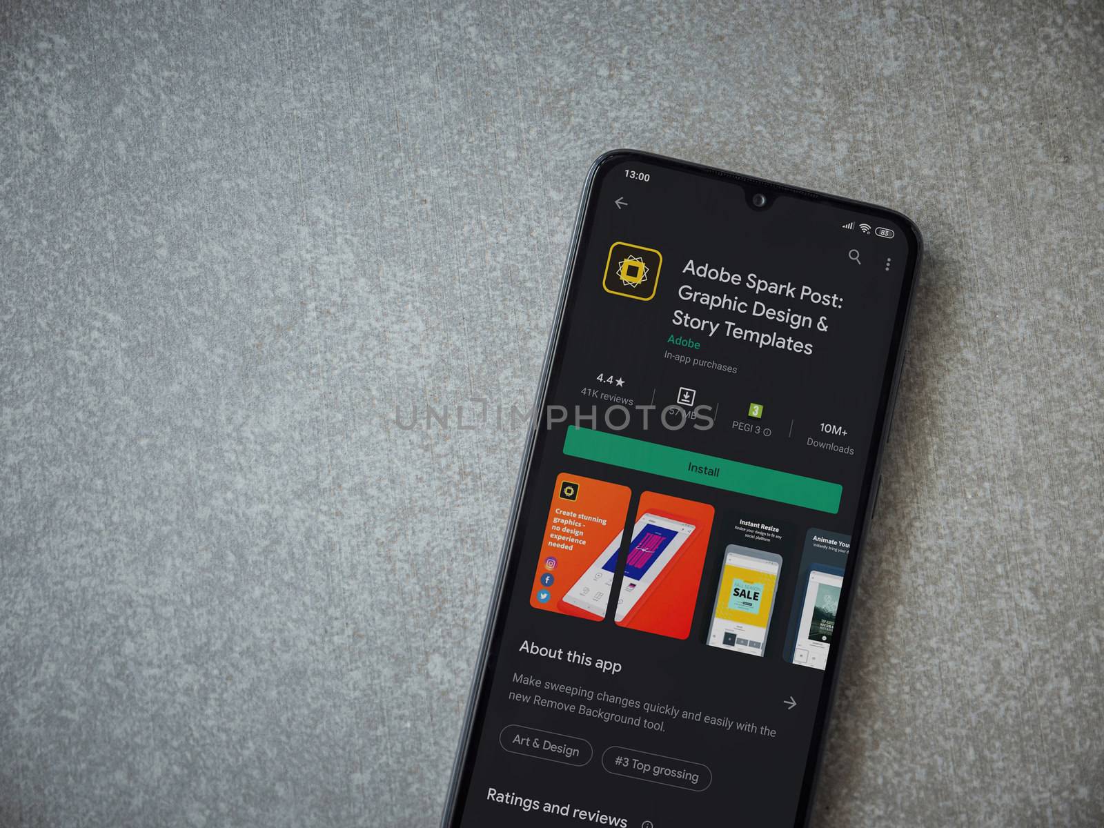 Lod, Israel - July 8, 2020: Adobe Spark Post - Graphic Design and Story Templates app play store page on the display of a black mobile smartphone on ceramic stone background.Top view flat lay with copy space