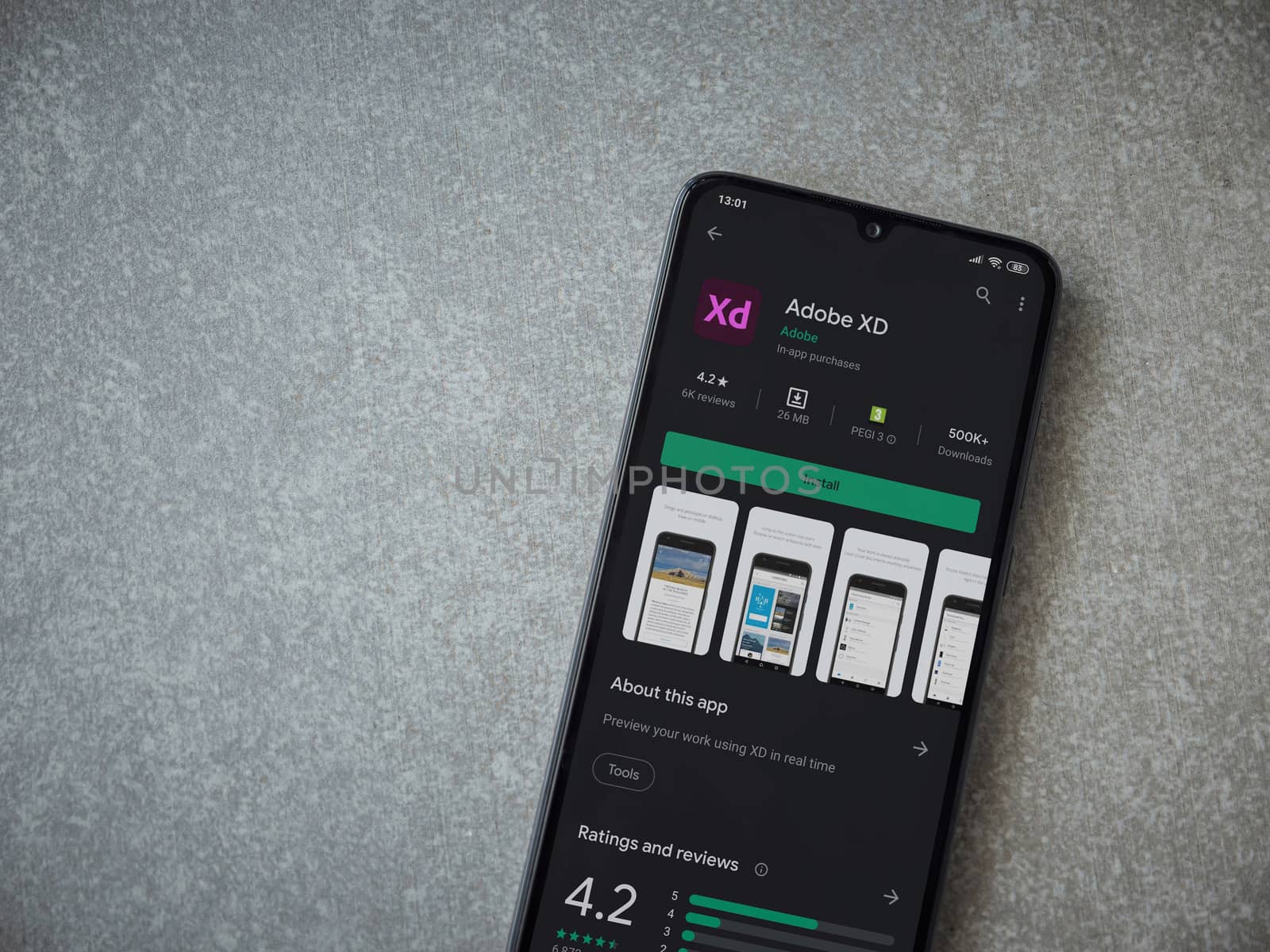 Lod, Israel - July 8, 2020: Adobe XD app play store page on the display of a black mobile smartphone on ceramic stone background. Top view flat lay with copy space. 