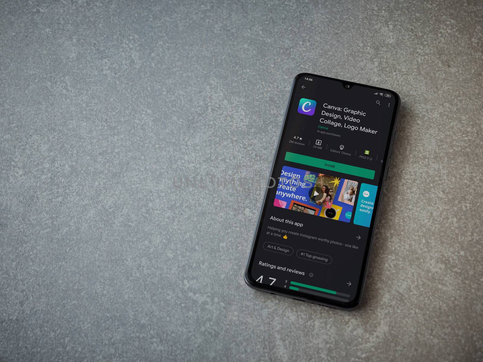 Lod, Israel - July 8, 2020: Canva - Graphic Design app play store page on the display of a black mobile smartphone on ceramic stone background. Top view flat lay with copy space. 