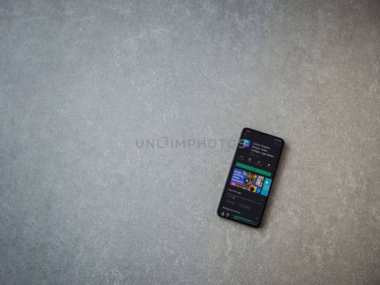 Lod, Israel - July 8, 2020: Canva - Graphic Design app play store page on the display of a black mobile smartphone on ceramic stone background. Top view flat lay with copy space. 
