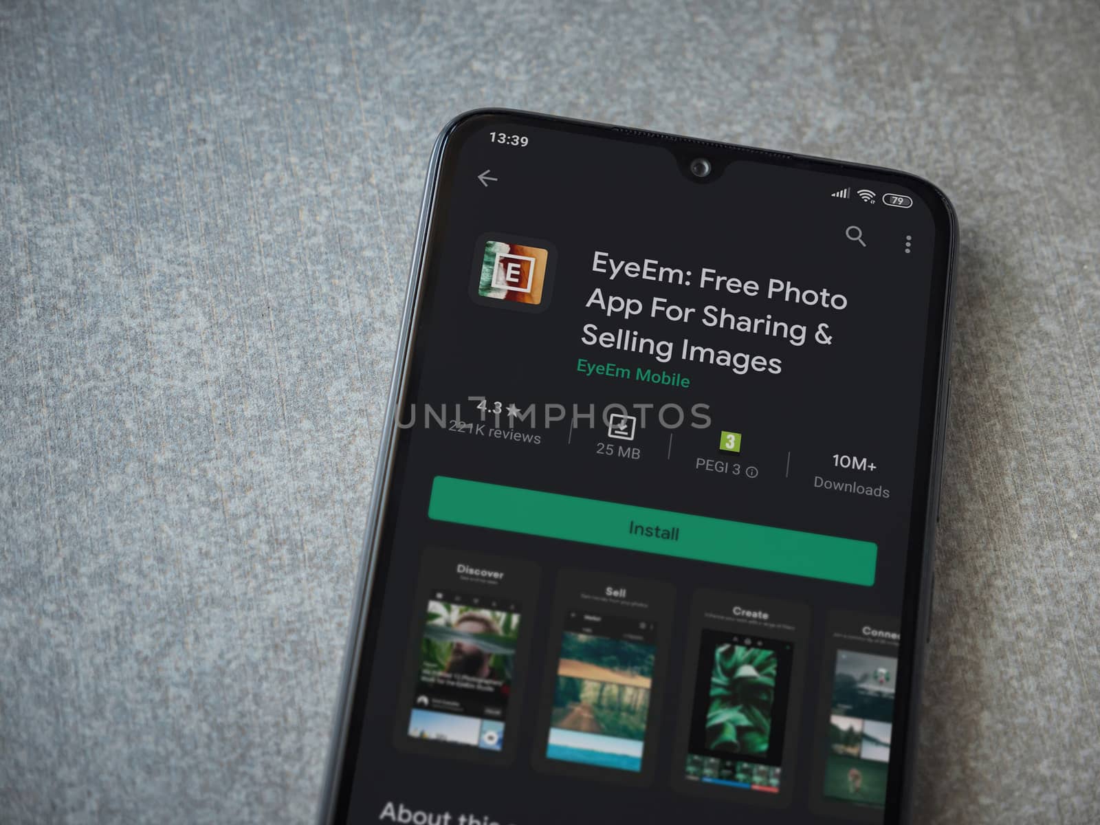 Lod, Israel - July 8, 2020: EyeEm - Sharing and Selling Images app play store page on the display of a black mobile smartphone on ceramic stone background. Top view flat lay with copy space.
