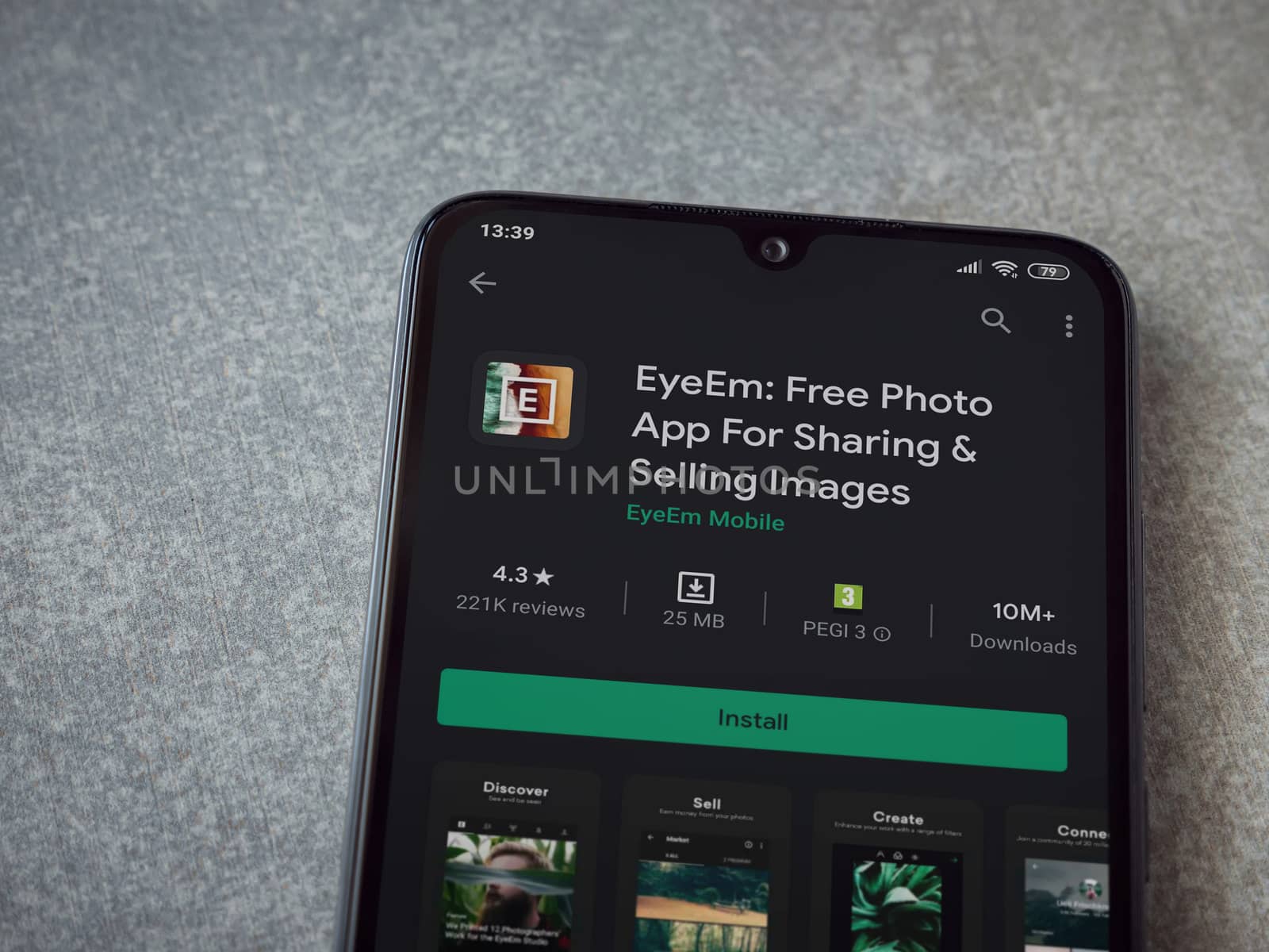 Lod, Israel - July 8, 2020: EyeEm - Sharing and Selling Images app play store page on the display of a black mobile smartphone on ceramic stone background. Top view flat lay with copy space.