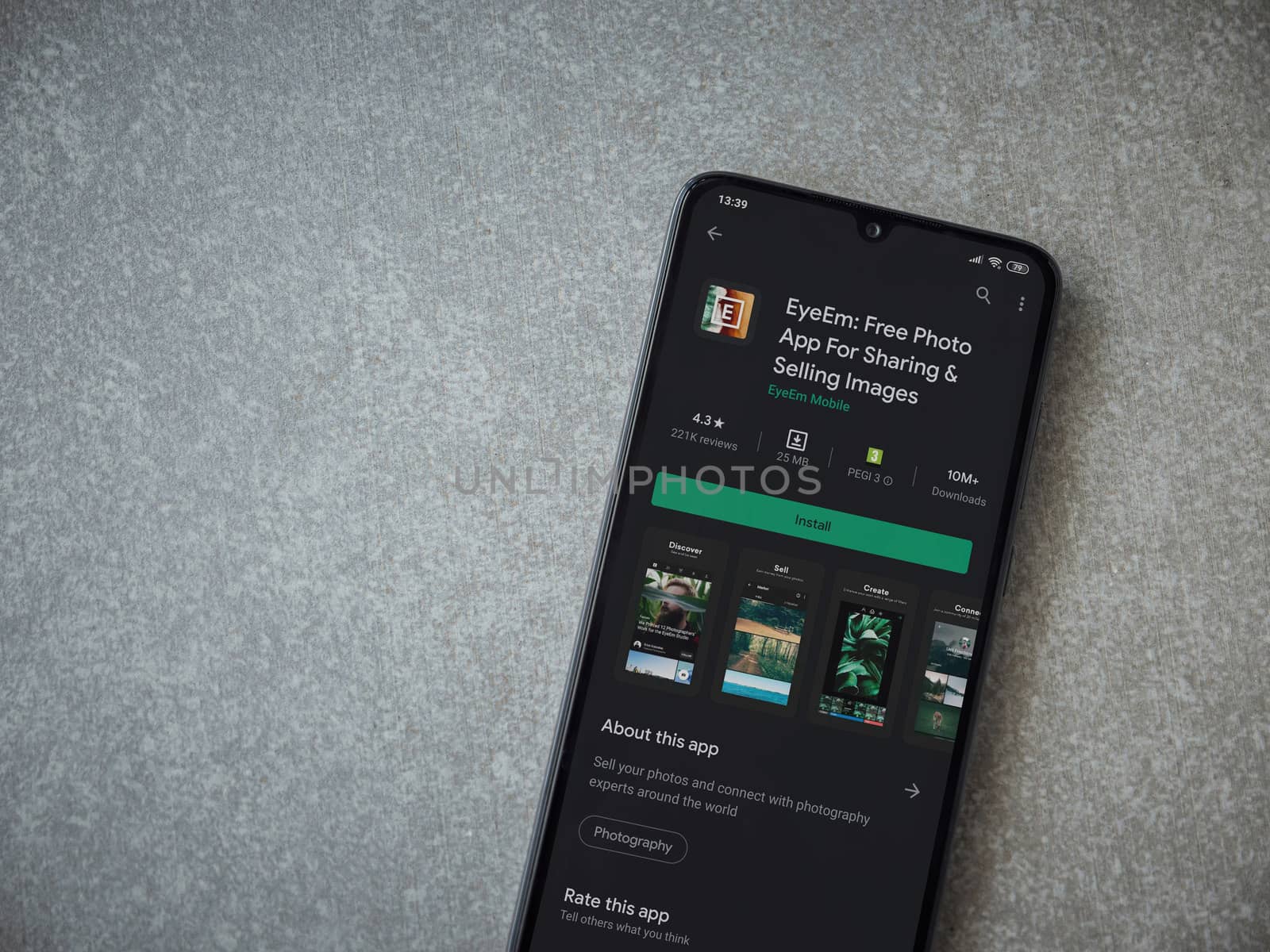 Lod, Israel - July 8, 2020: EyeEm - Sharing and Selling Images app play store page on the display of a black mobile smartphone on ceramic stone background. Top view flat lay with copy space.