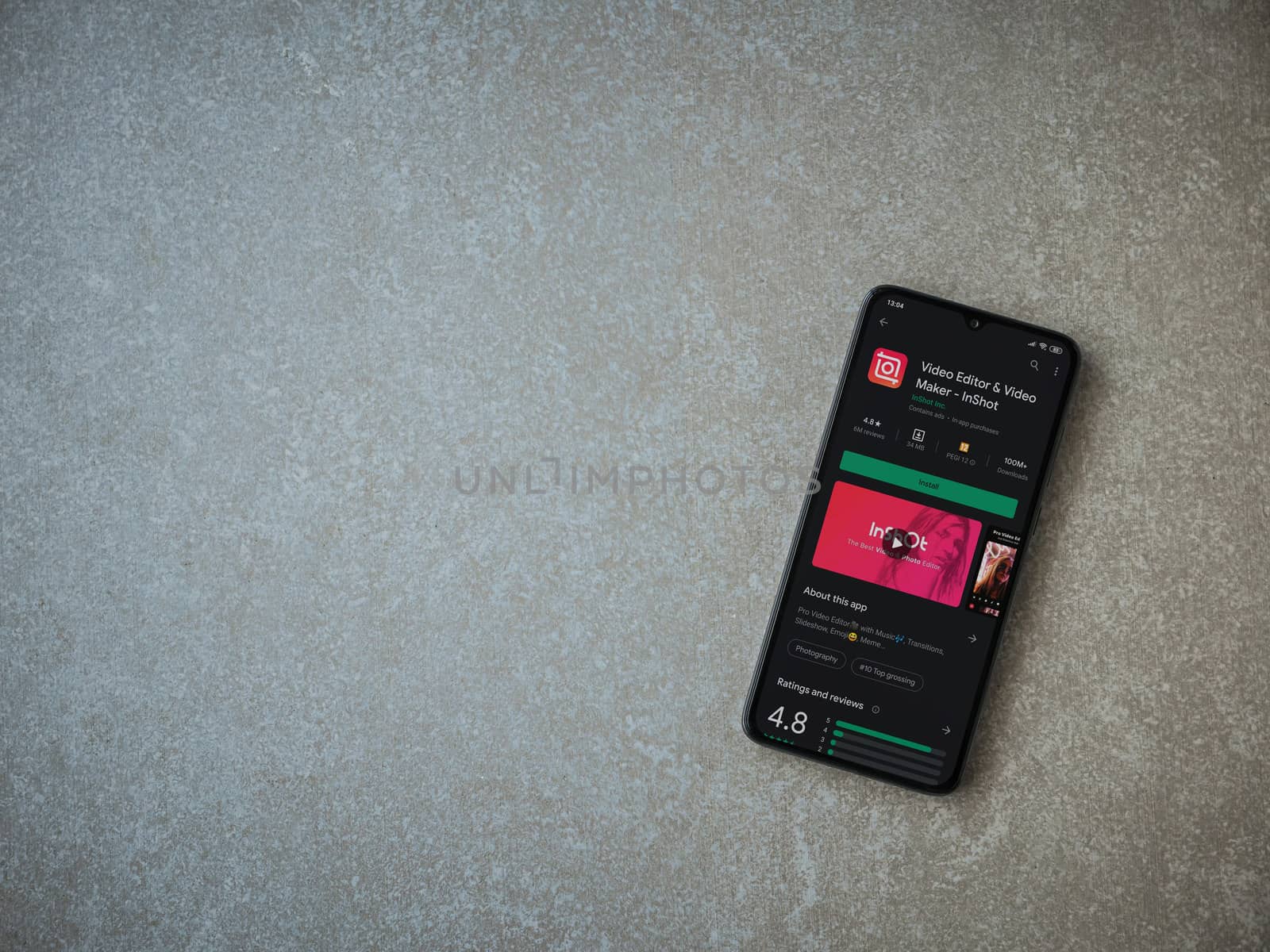 Lod, Israel - July 8, 2020: InShot - Video Editor and Movie Maker app play store page on the display of a black mobile smartphone on ceramic stone background. Top view flat lay with copy space.