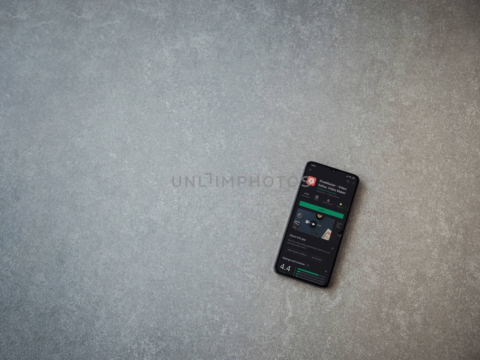 Lod, Israel - July 8, 2020: KineMaster - Video Editor and Movie Maker app play store page on the display of a black mobile smartphone on ceramic stone background. Top view flat lay with copy space.