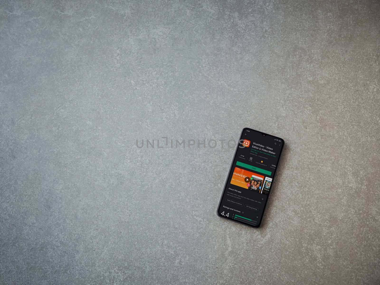 Lod, Israel - July 8, 2020: VivaVideo - Video Editor and Movie Maker app play store page on the display of a black mobile smartphone on ceramic stone background. Top view flat lay with copy space.