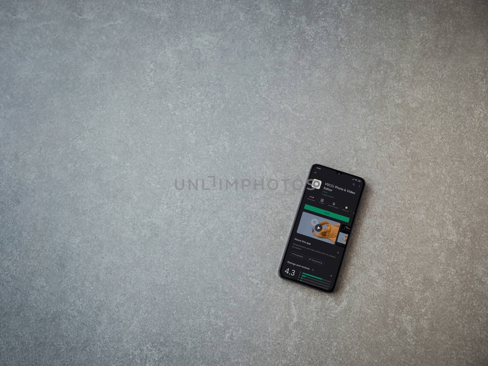 Lod, Israel - July 8, 2020: VSCO - Photo and Video Editor app play store page on the display of a black mobile smartphone on ceramic stone background. Top view flat lay with copy space. 