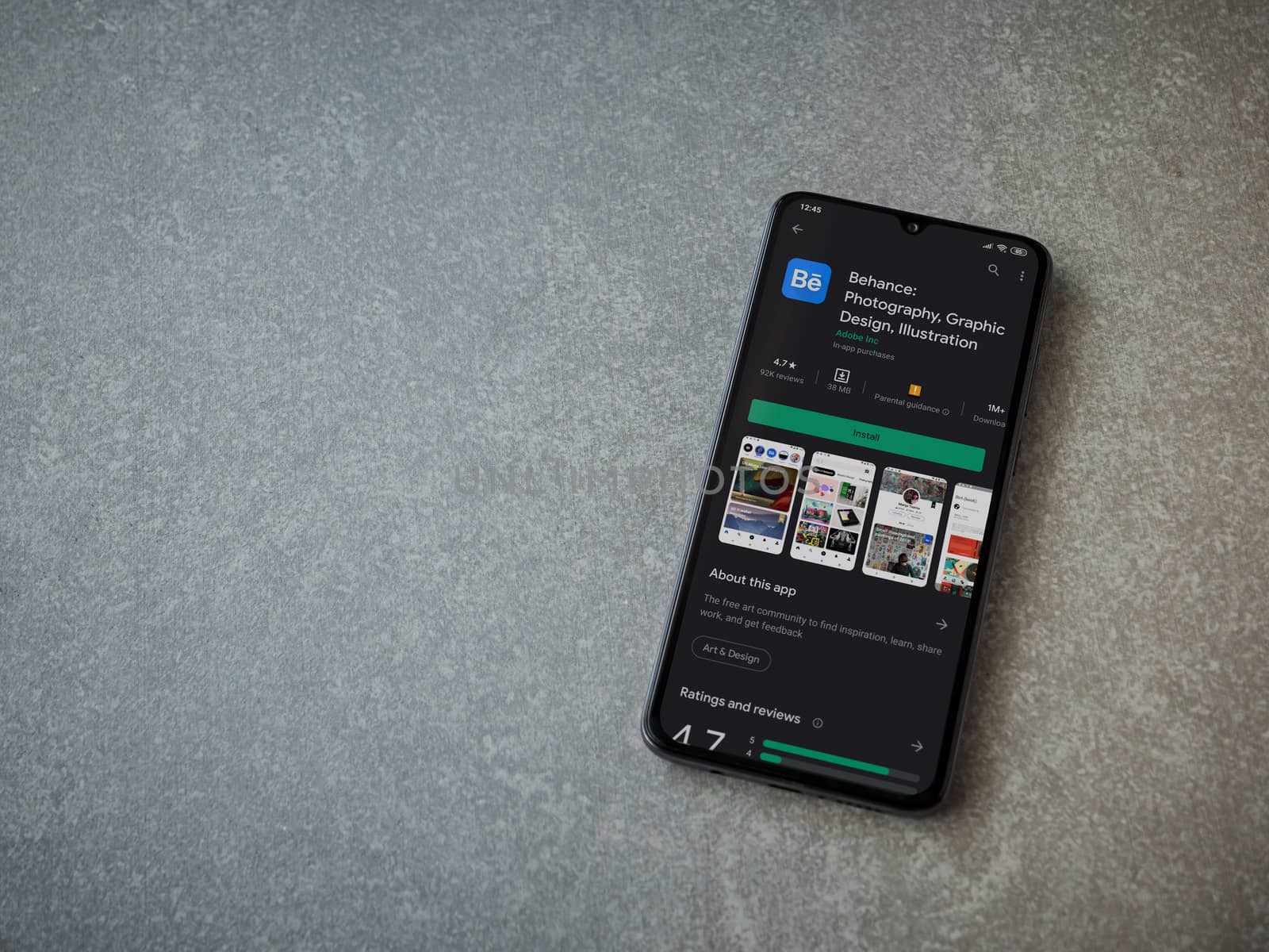 Lod, Israel - July 8, 2020: Adobe Behance app play store page on the display of a black mobile smartphone on ceramic stone background. Top view flat lay with copy space. 