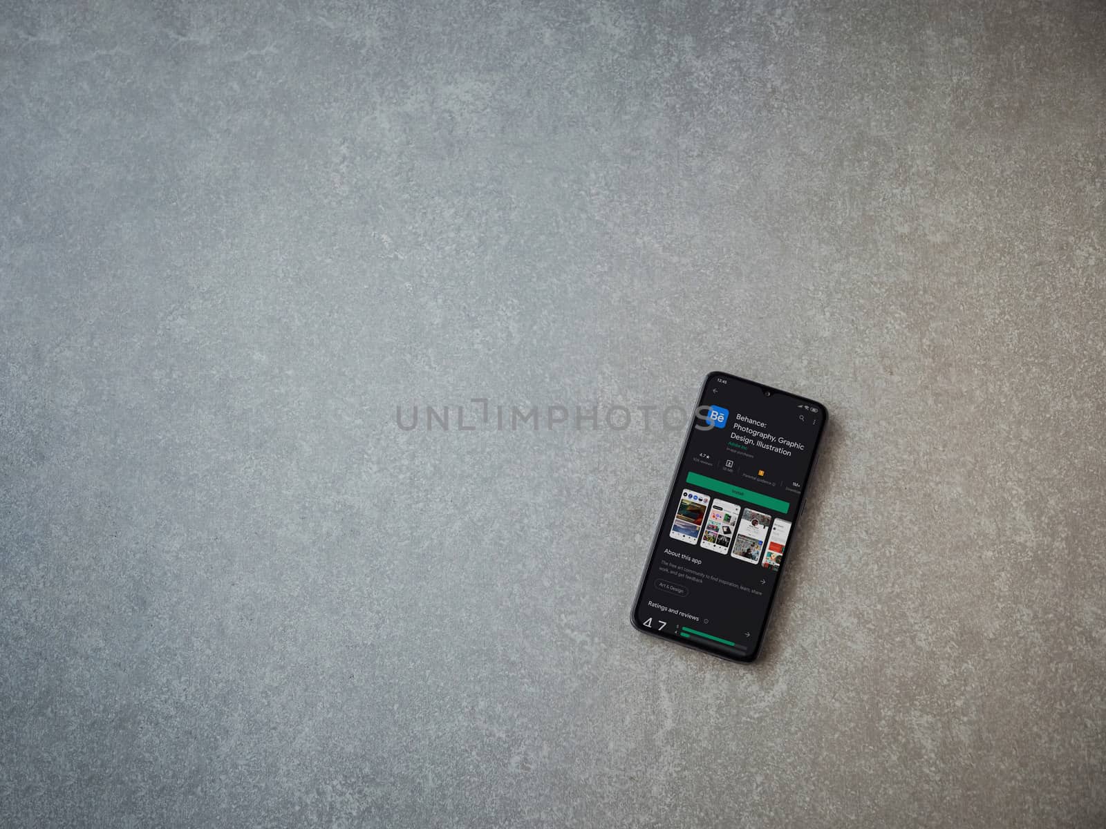 Lod, Israel - July 8, 2020: Adobe Behance app play store page on the display of a black mobile smartphone on ceramic stone background. Top view flat lay with copy space. 
