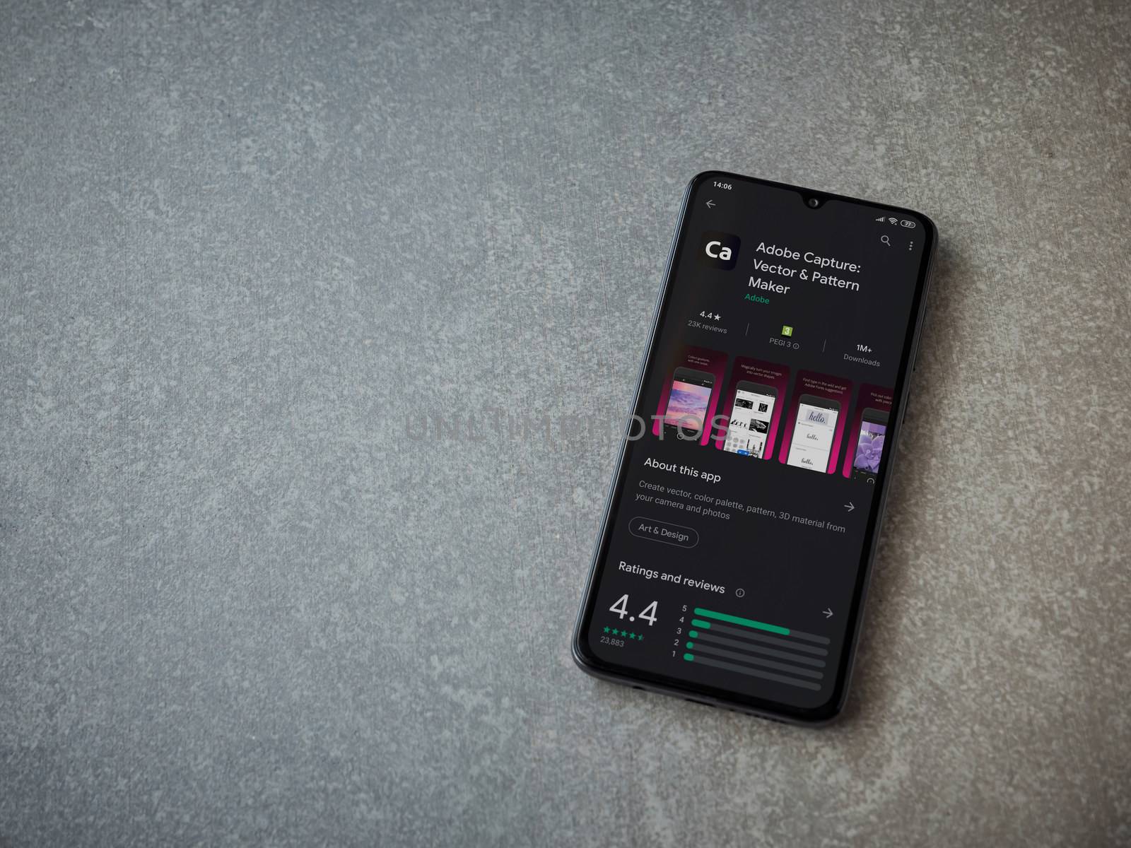 Lod, Israel - July 8, 2020: Adobe Capture - Vector and Pattern Maker app play store page on the display of a black mobile smartphone on ceramic stone background. Top view flat lay with copy space.