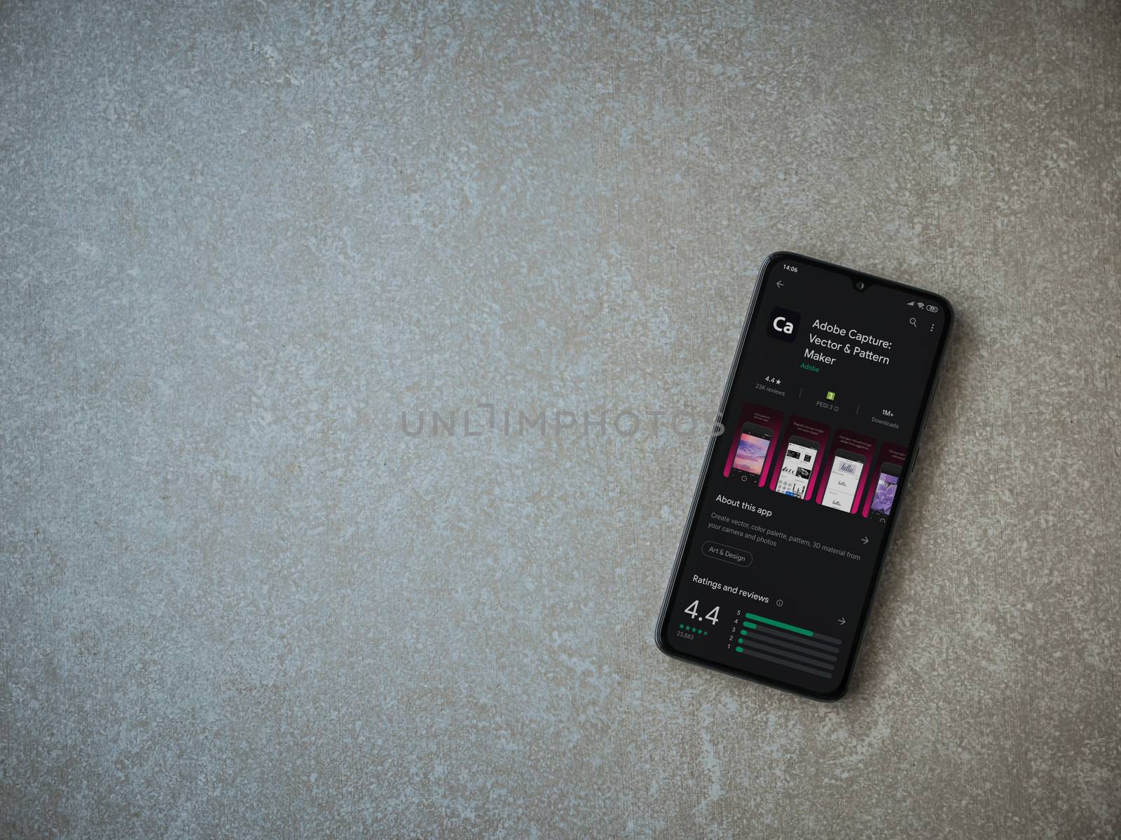 Lod, Israel - July 8, 2020: Adobe Capture - Vector and Pattern Maker app play store page on the display of a black mobile smartphone on ceramic stone background. Top view flat lay with copy space.