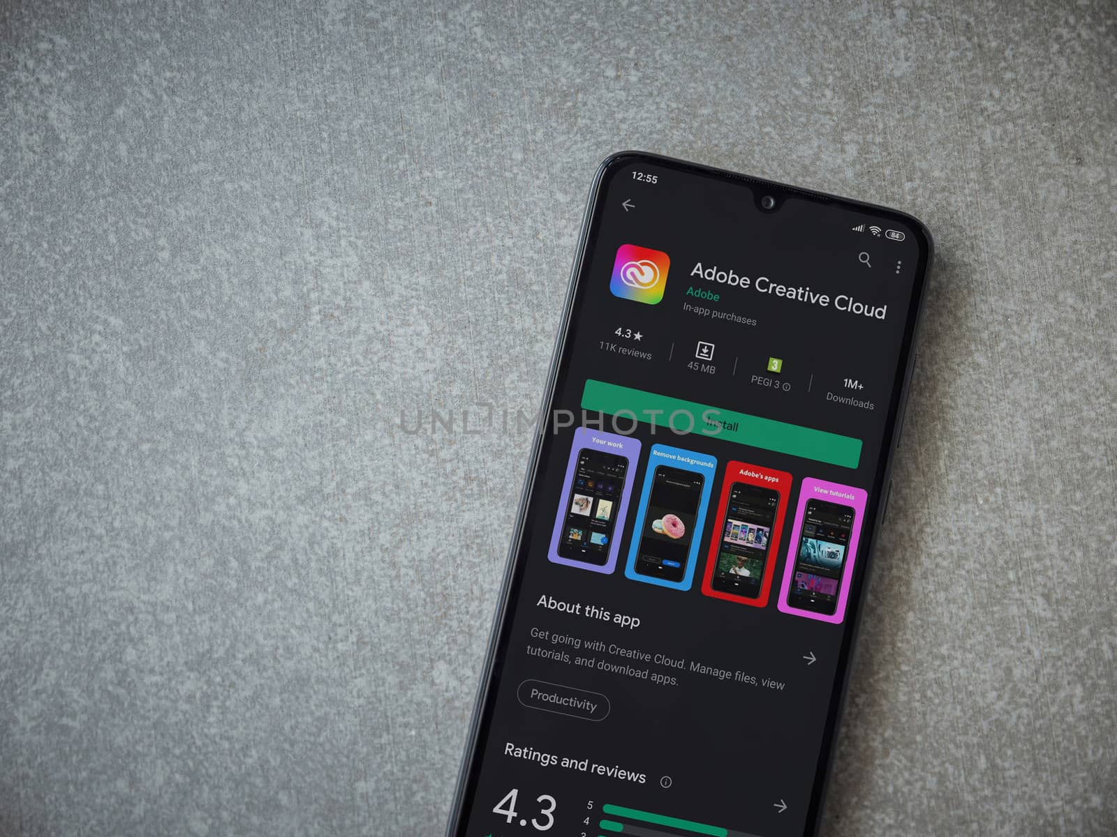 Lod, Israel - July 8, 2020: Adobe Creative Cloud app play store page on the display of a black mobile smartphone on ceramic stone background. Top view flat lay with copy space.