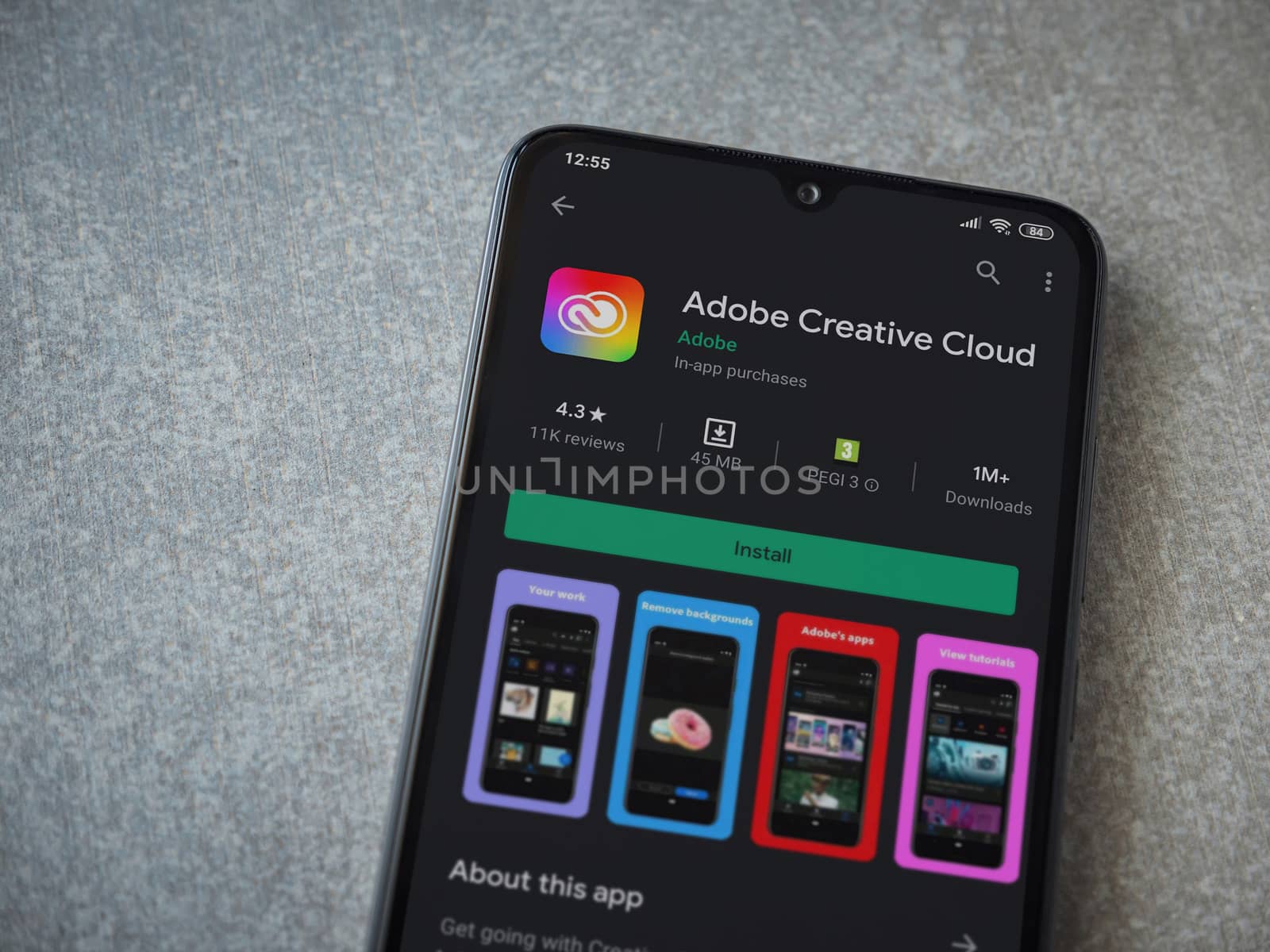Lod, Israel - July 8, 2020: Adobe Creative Cloud app play store page on the display of a black mobile smartphone on ceramic stone background. Top view flat lay with copy space.