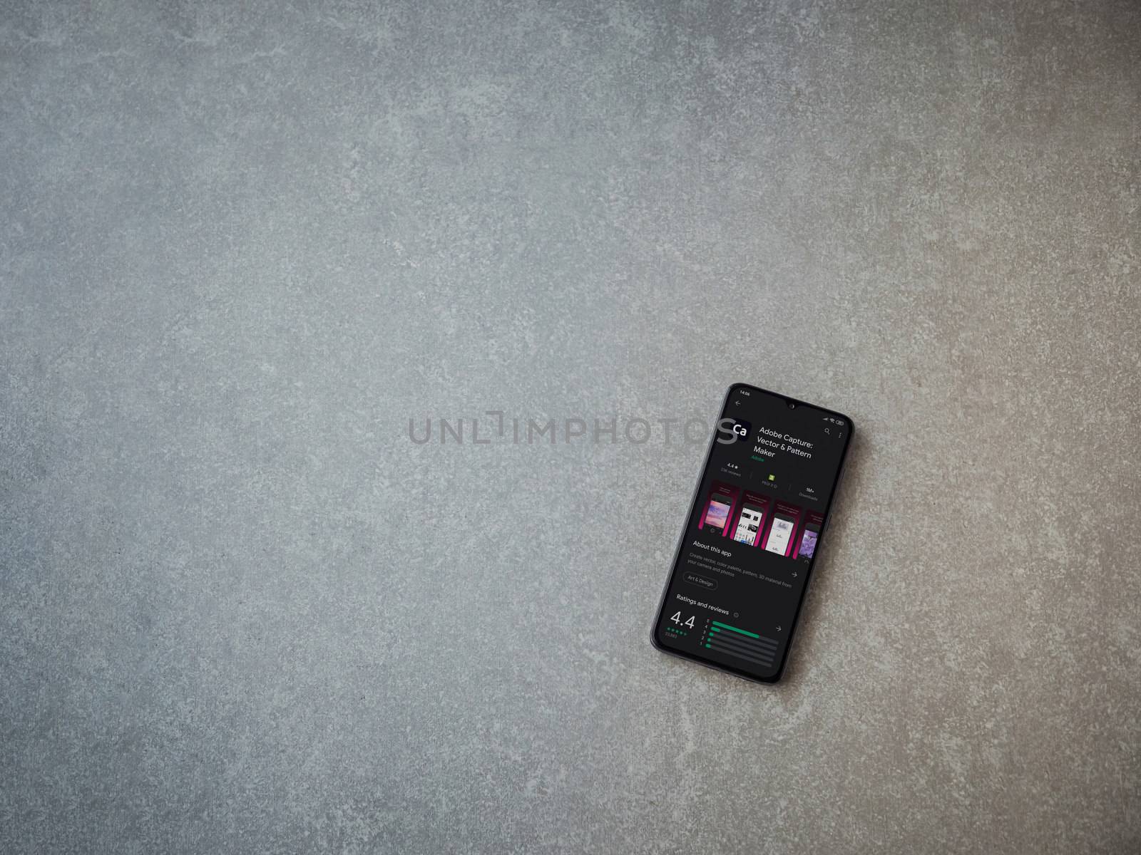 Lod, Israel - July 8, 2020: Adobe Capture - Vector and Pattern Maker app play store page on the display of a black mobile smartphone on ceramic stone background. Top view flat lay with copy space.