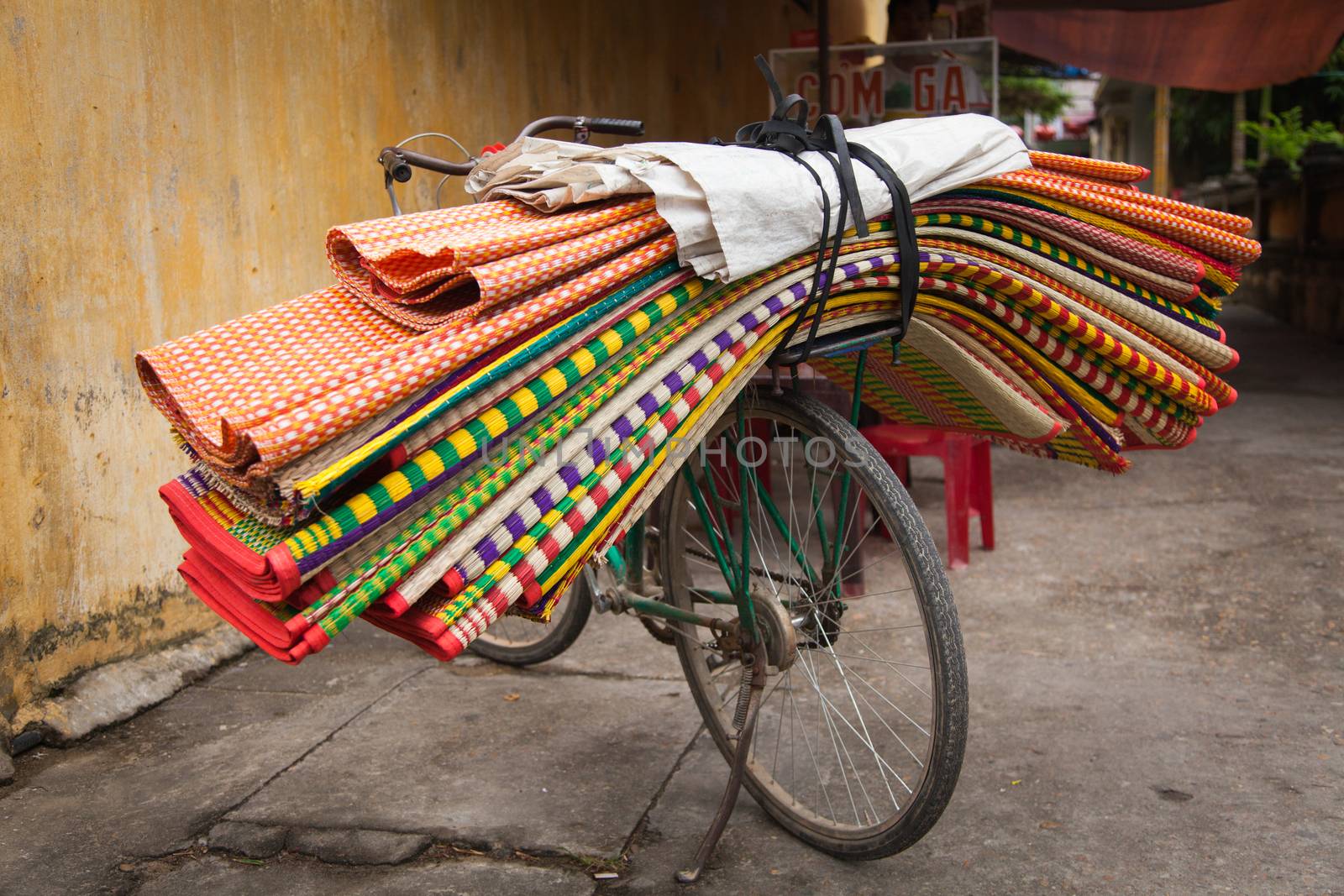 Hoi An Vietnam 24/12/2013 overloaded bicycle with floor coverings, mats and fabrics transporting goods. 2 wheel vehicles with huge amounts of products transporting around the city. High quality photo